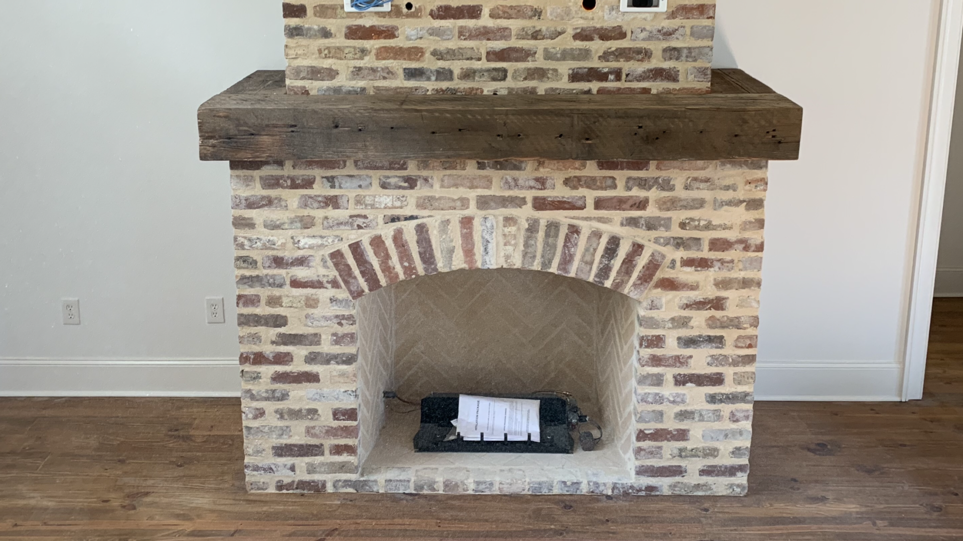 a brick fireplace with a wooden mantle in a living room