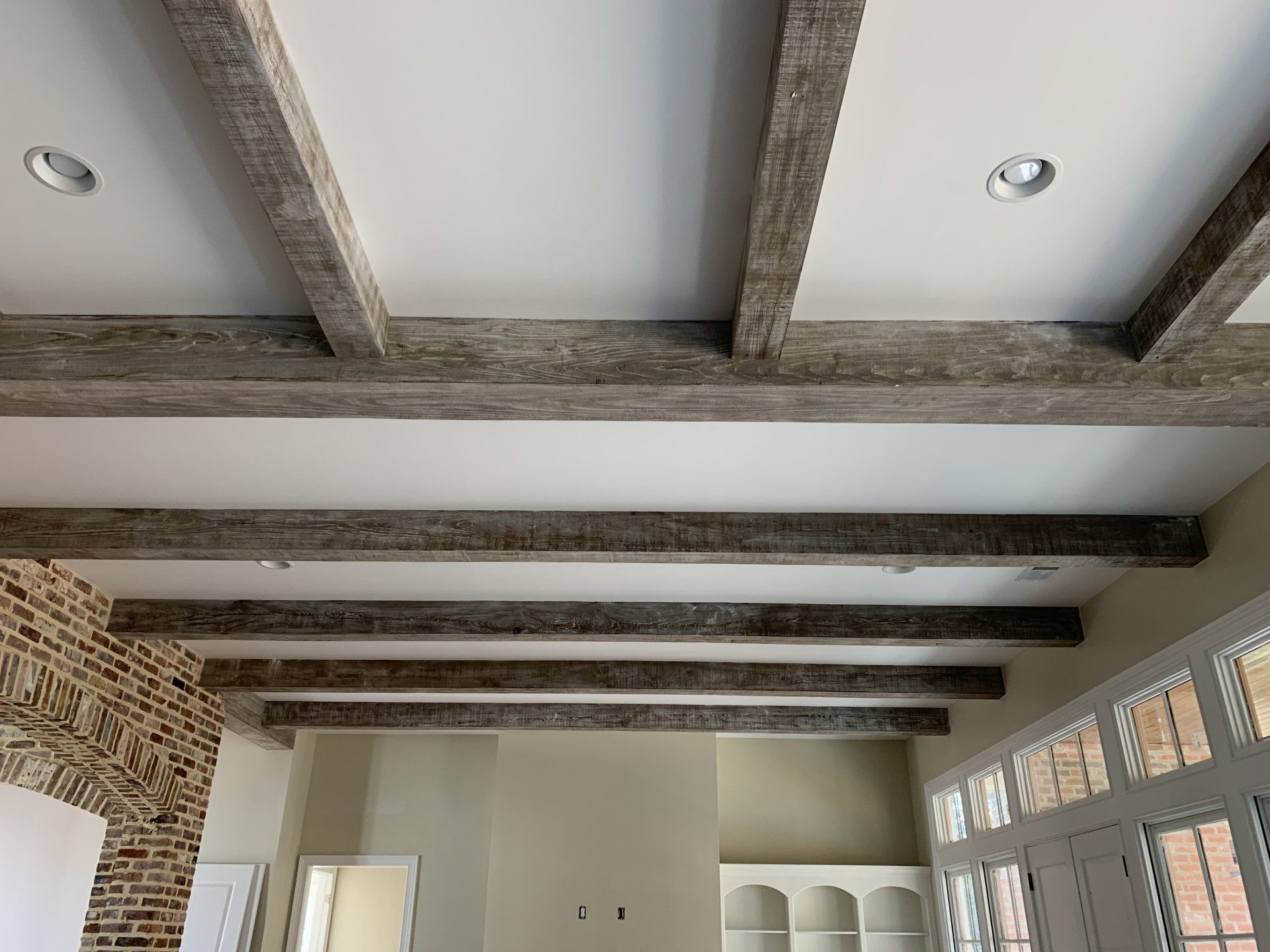 the ceiling of a room with wooden beams and a brick wall