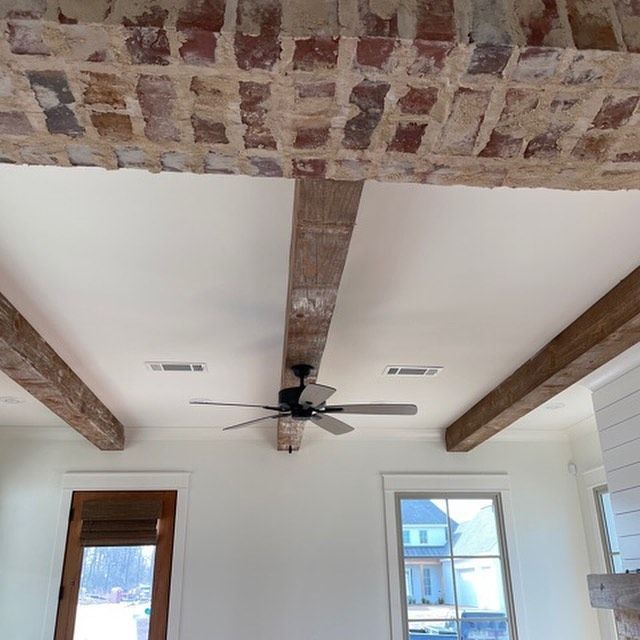 a room with a ceiling fan and brick beams