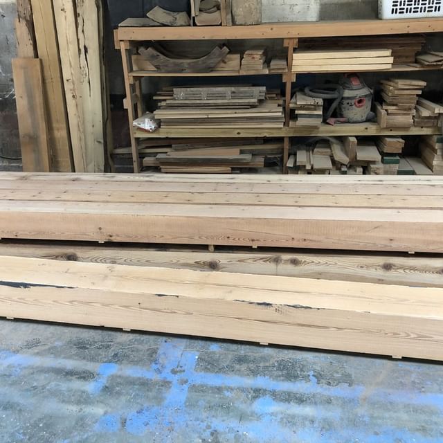 a stack of wooden beams sits in front of a shelf full of wood