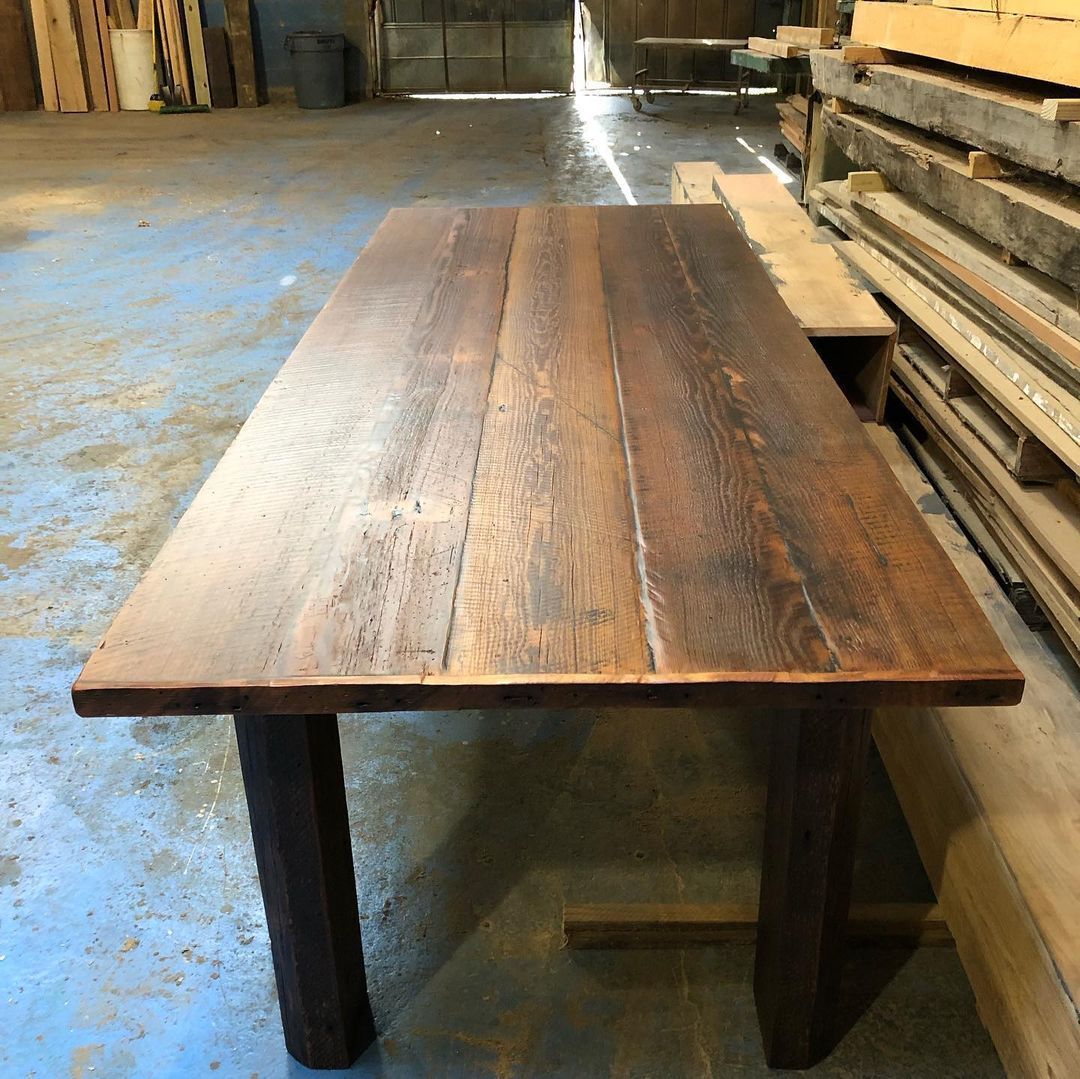 a wooden table is sitting in a warehouse next to a pile of wood