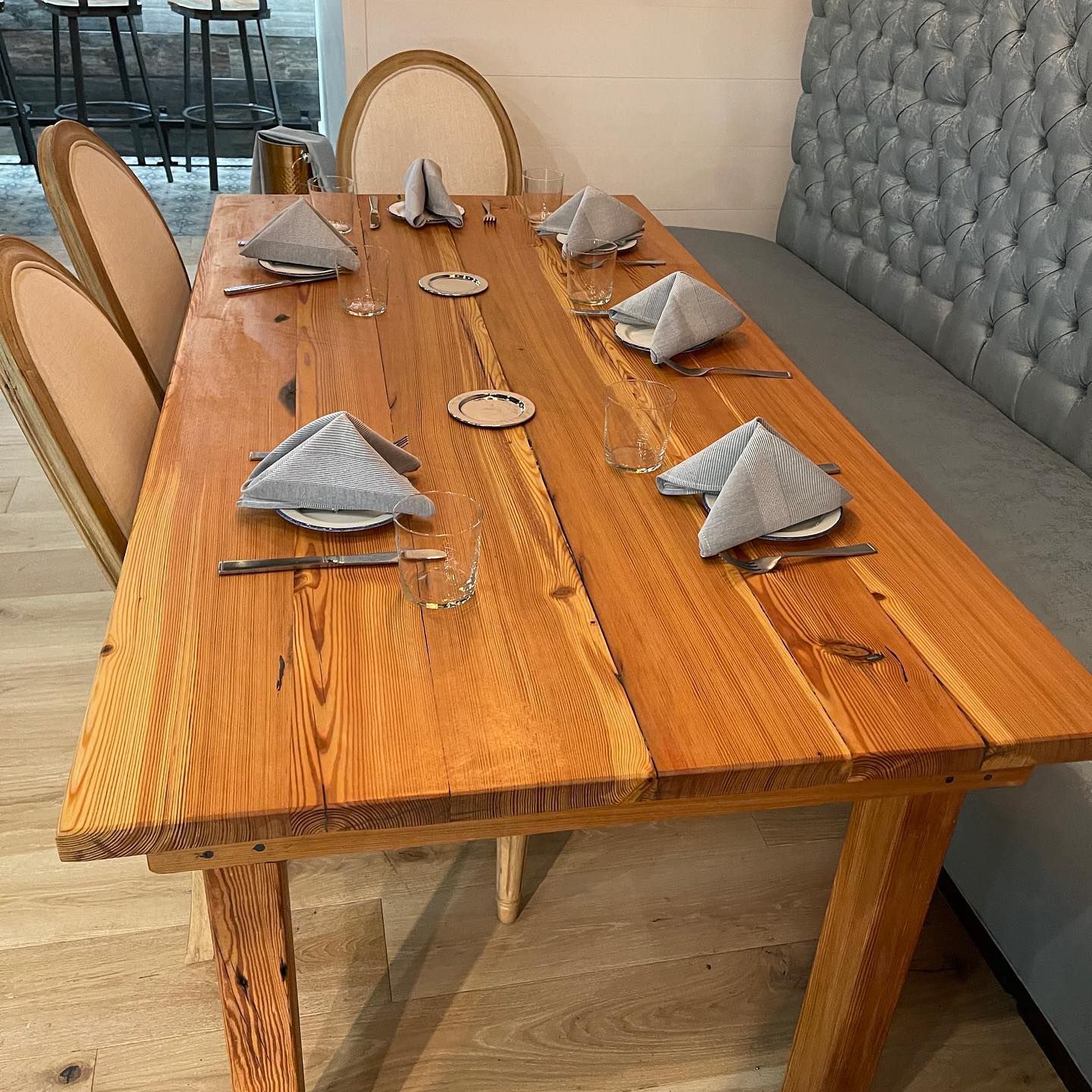 A long wooden table with plates and napkins on it.