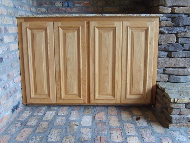a wooden cabinet is sitting on a brick floor next to a stone wall
