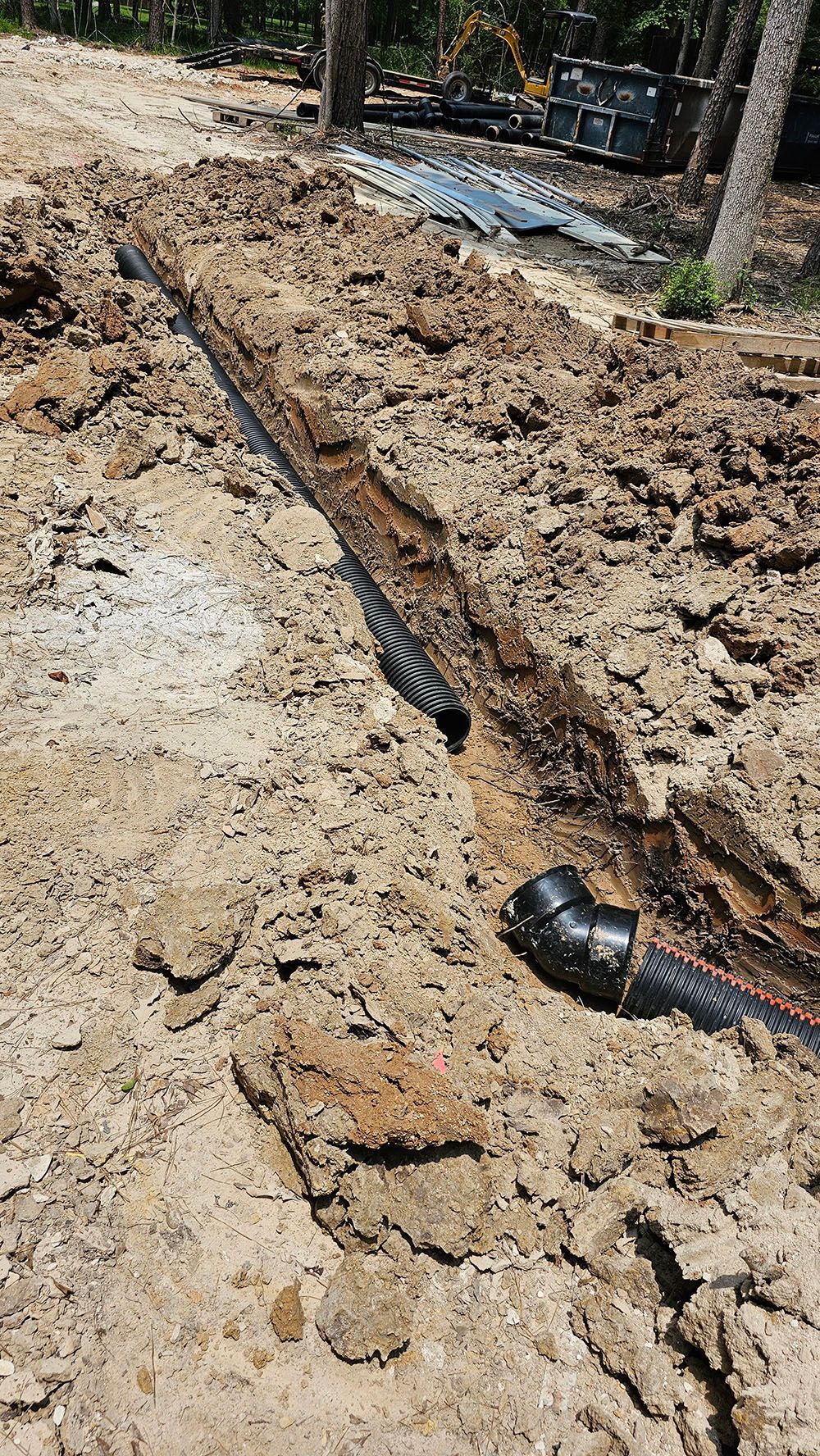 A drain pipe is being installed in the dirt.