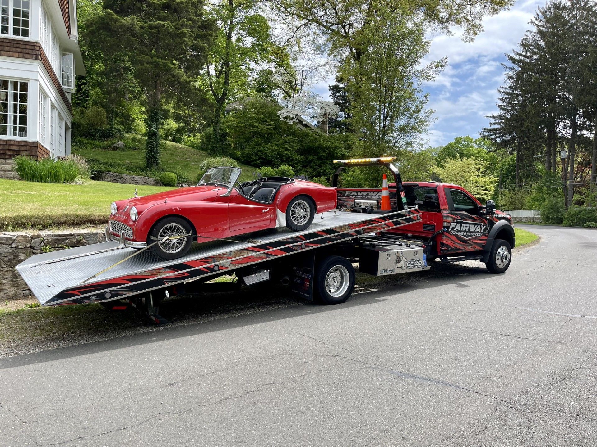 A red car is being towed by a tow truck.