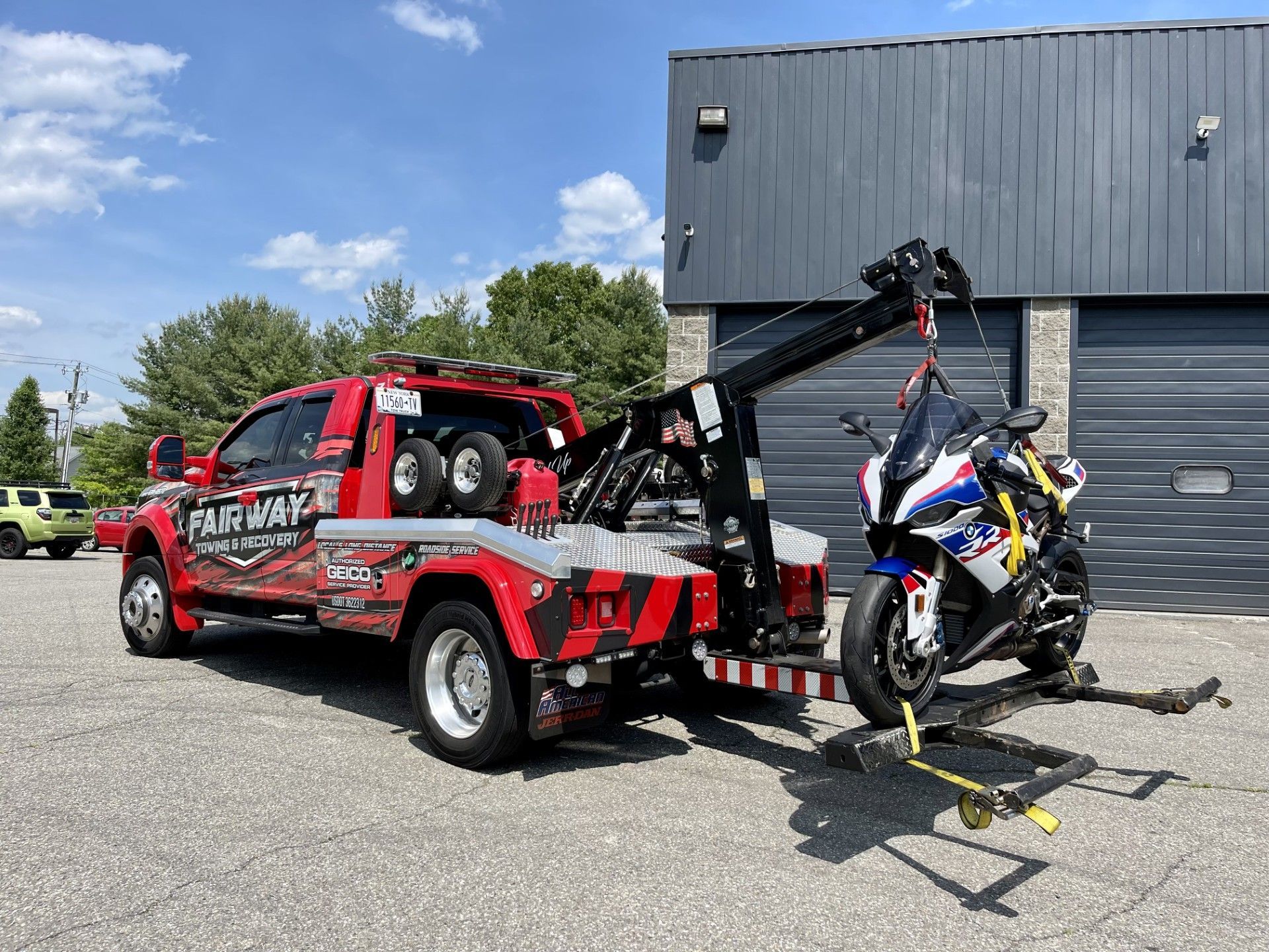 A tow truck is towing a motorcycle in a parking lot.