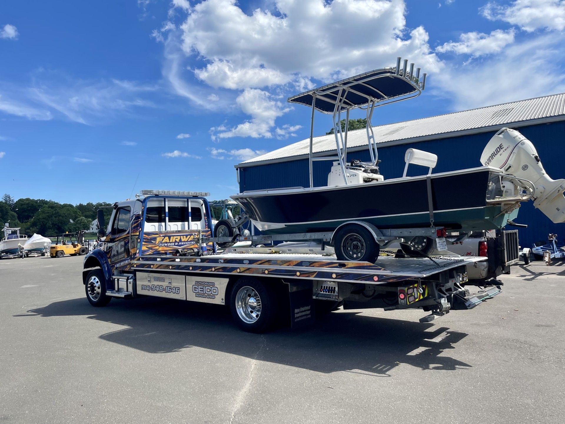 A tow truck is towing a boat in a parking lot.