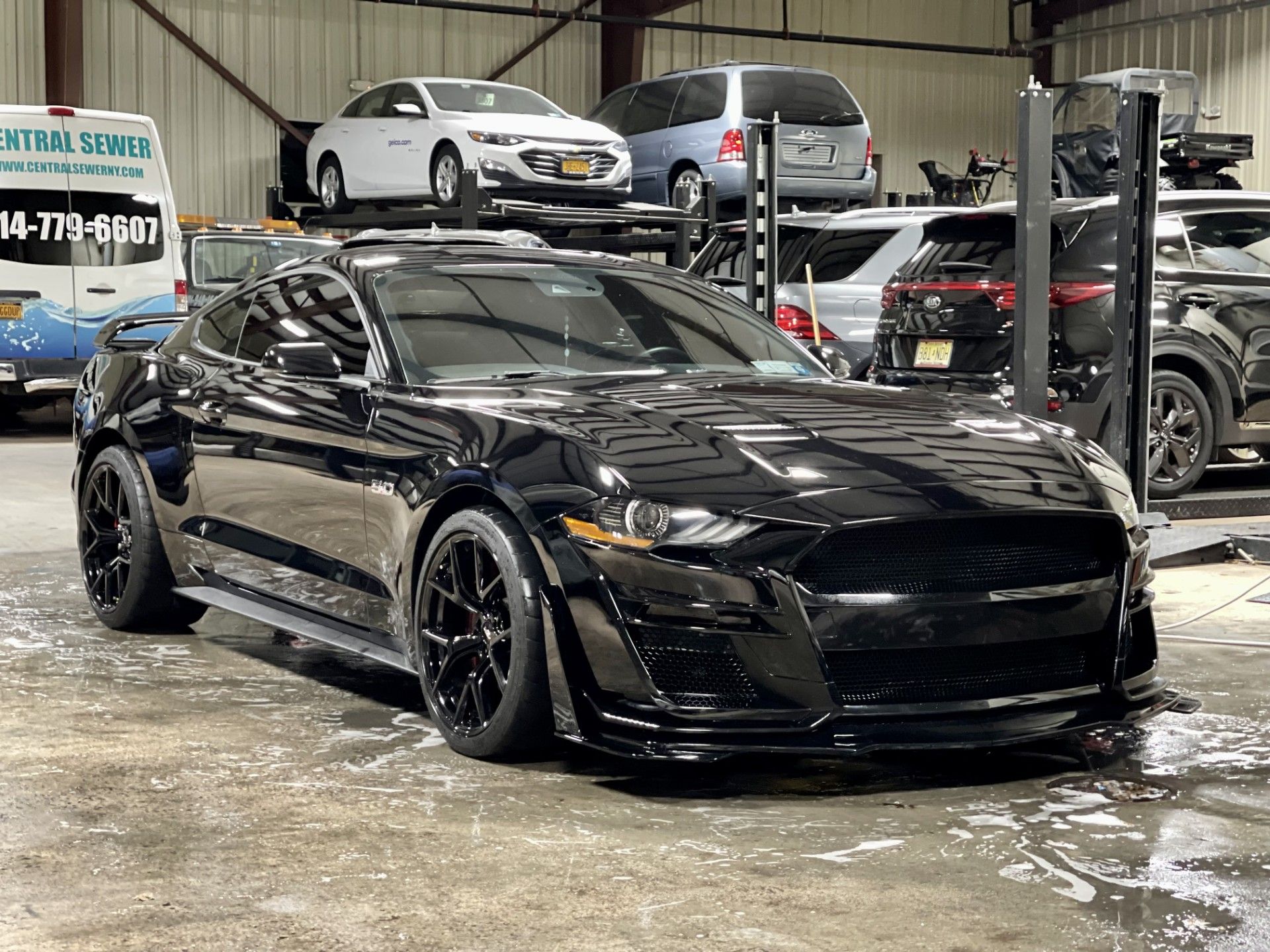 A black Ford Mustang is parked in a garage.