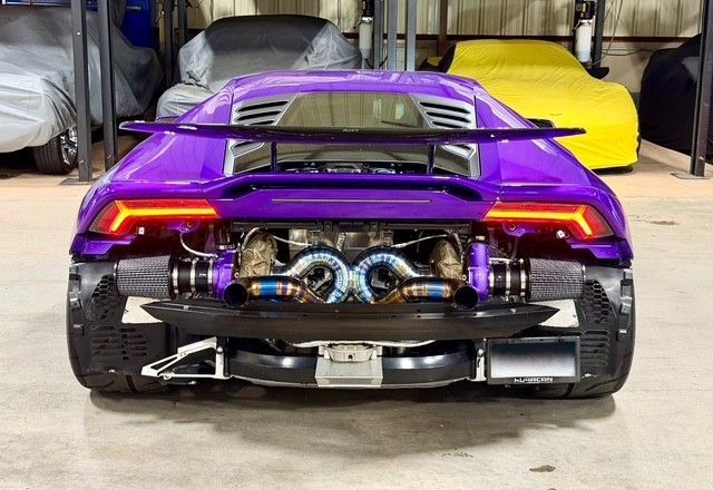 Purple Lamborghini with exposed engine, rear view, in a garage.