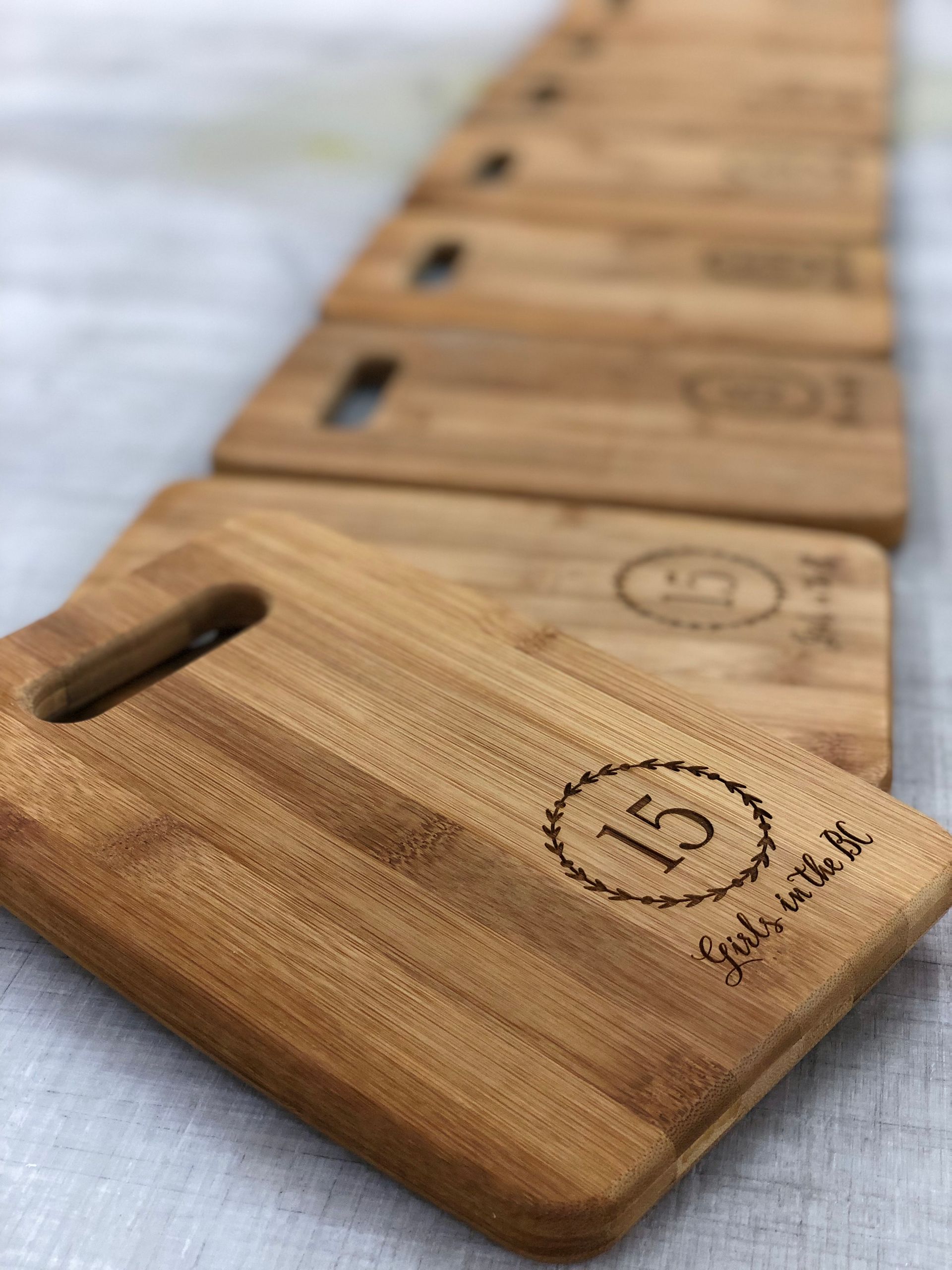 A row of wooden cutting boards are lined up on a table.