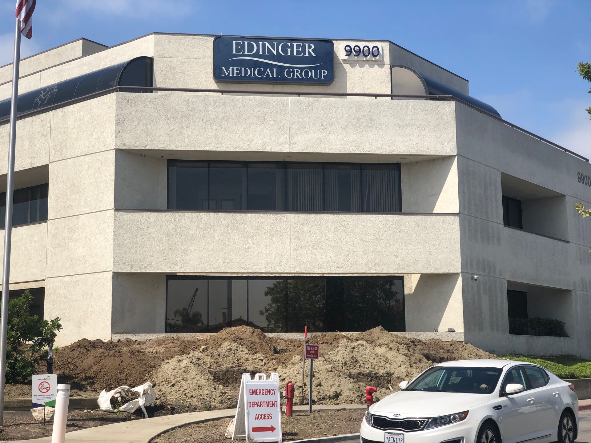 A white car is parked in front of a building that says edinger medical group