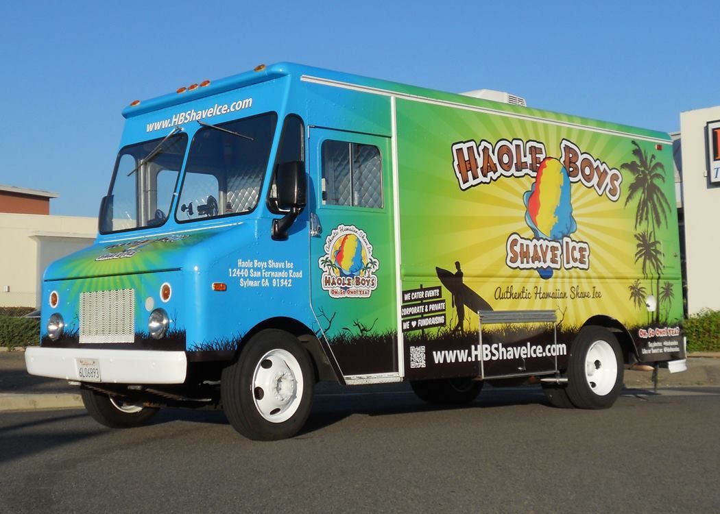 A blue and green food truck is parked in a parking lot