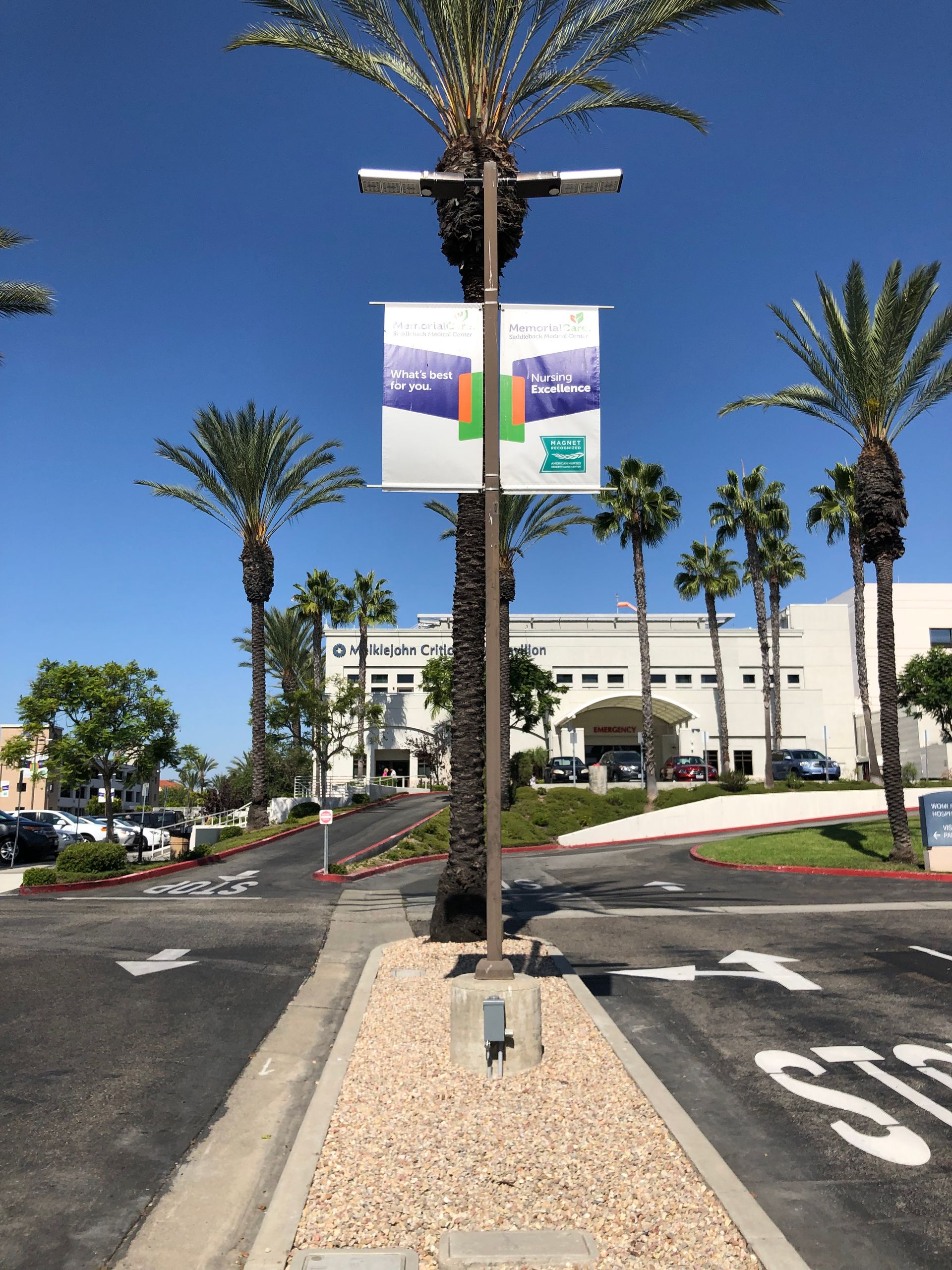 A sign hanging from a pole in front of a parking lot