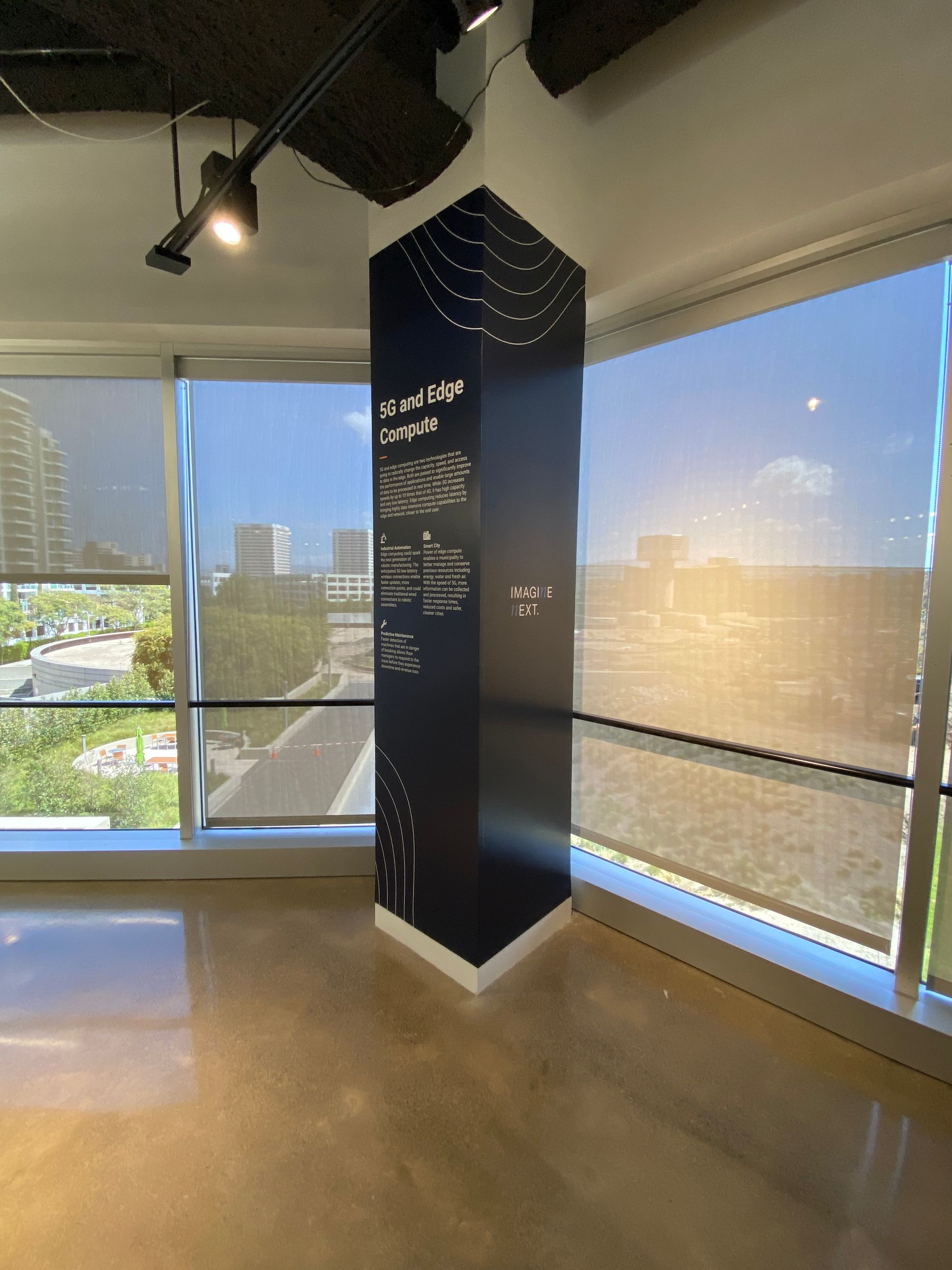 An empty room with a large window and a black pillar