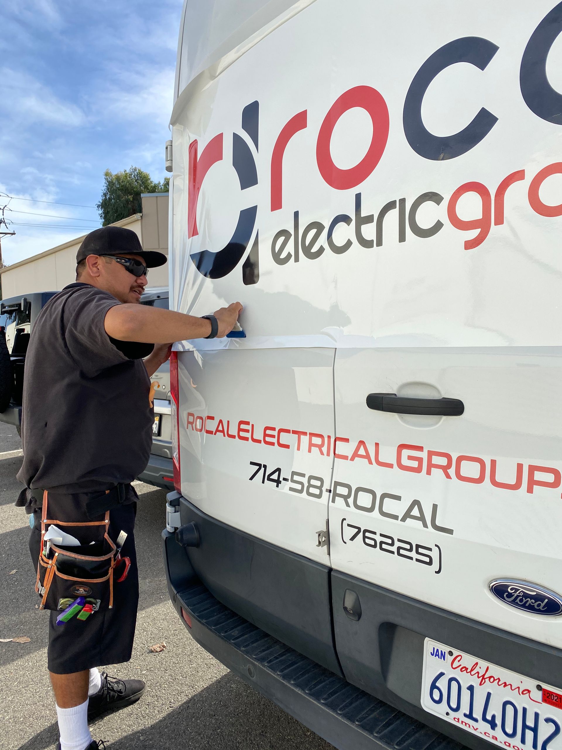 A man is working on the back of a ford van.