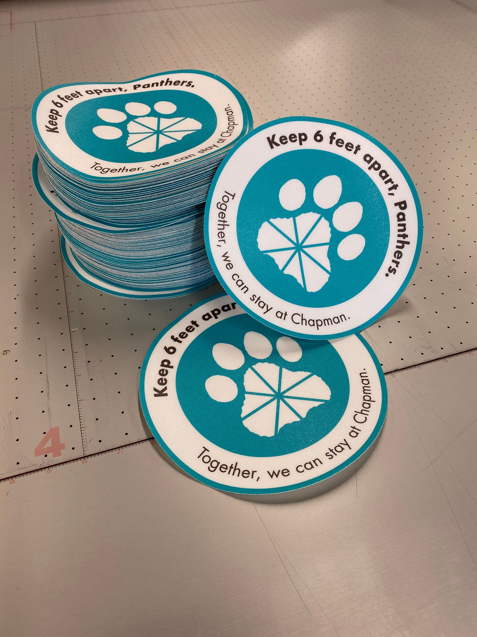 A stack of stickers that say keep 6 feet apart