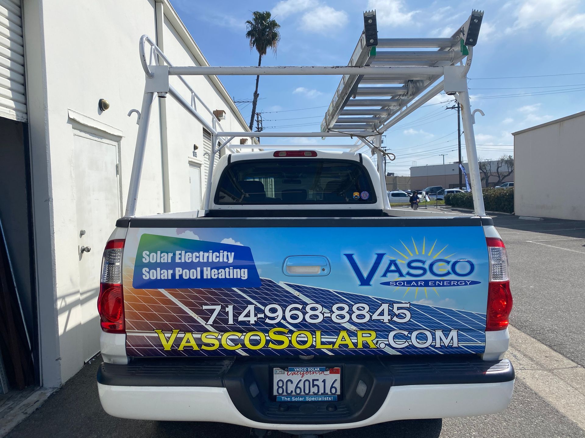 A truck with a ladder on the back is parked in front of a building.