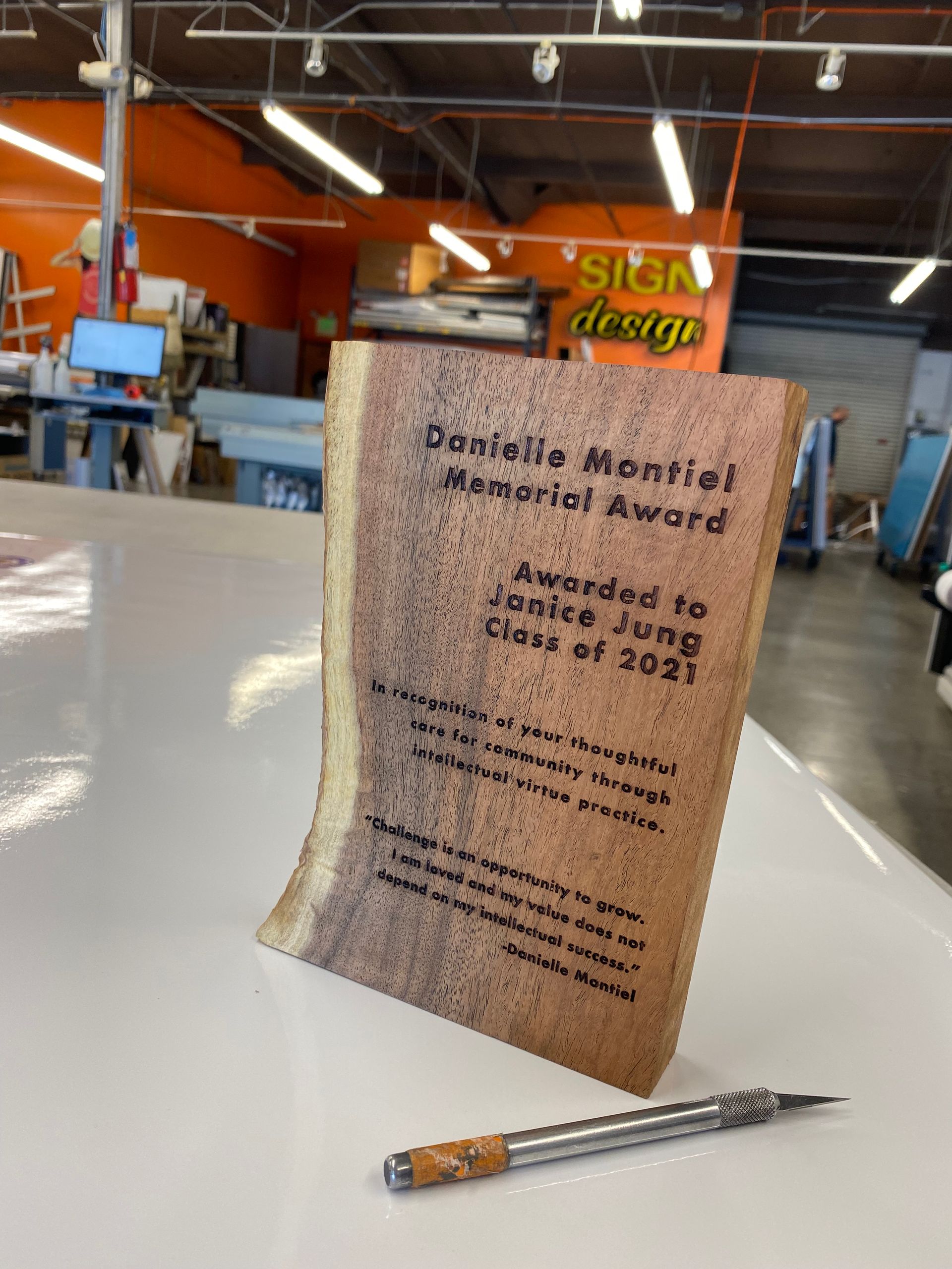 A wooden plaque is sitting on a table next to a pen.