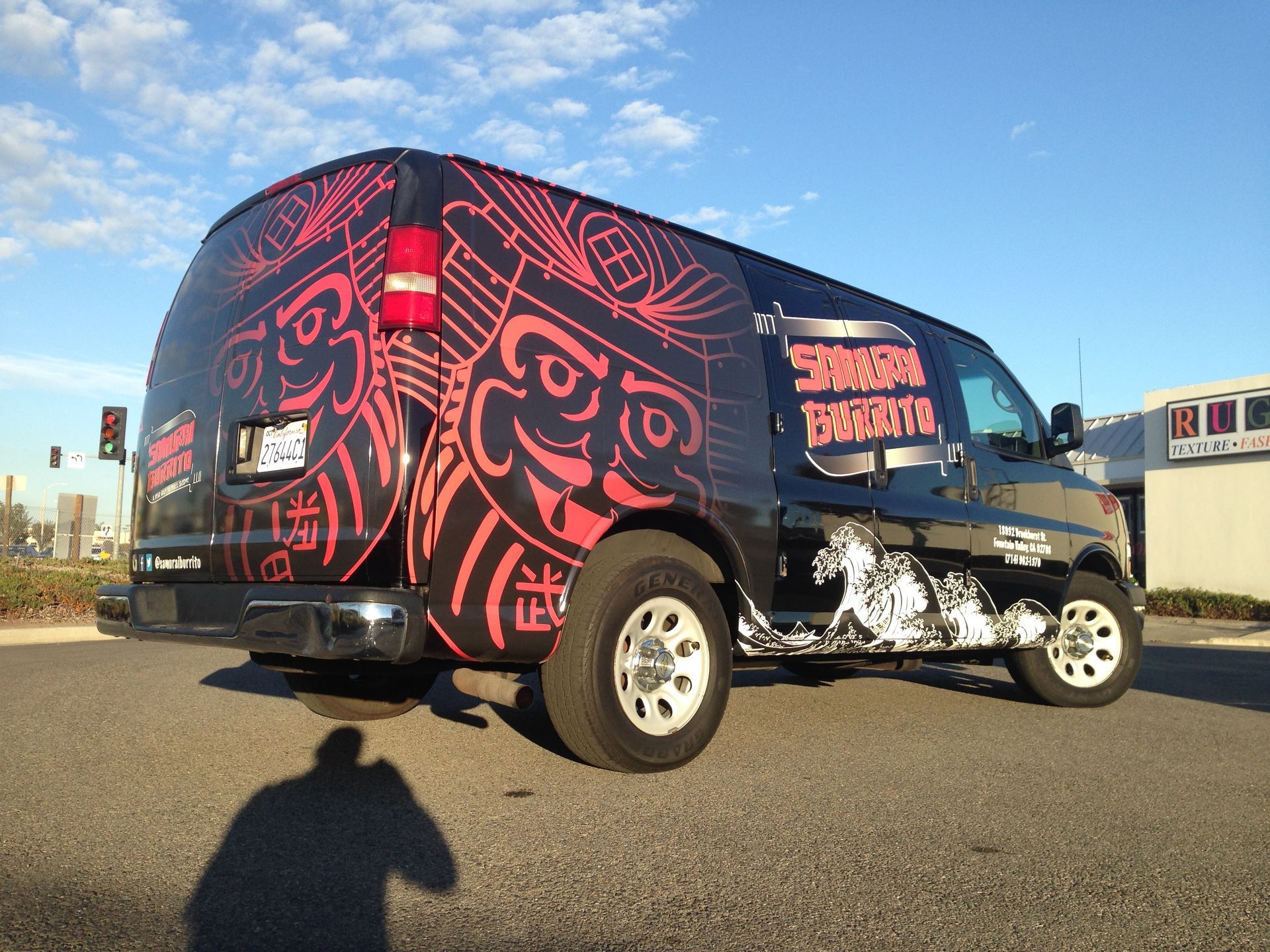 A black van with a motorcycle on the back is parked on the side of the road.