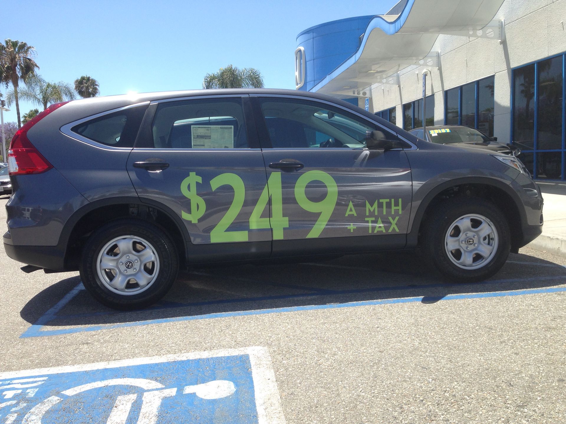 A car with the price of $ 249 is parked in a handicapped parking spot