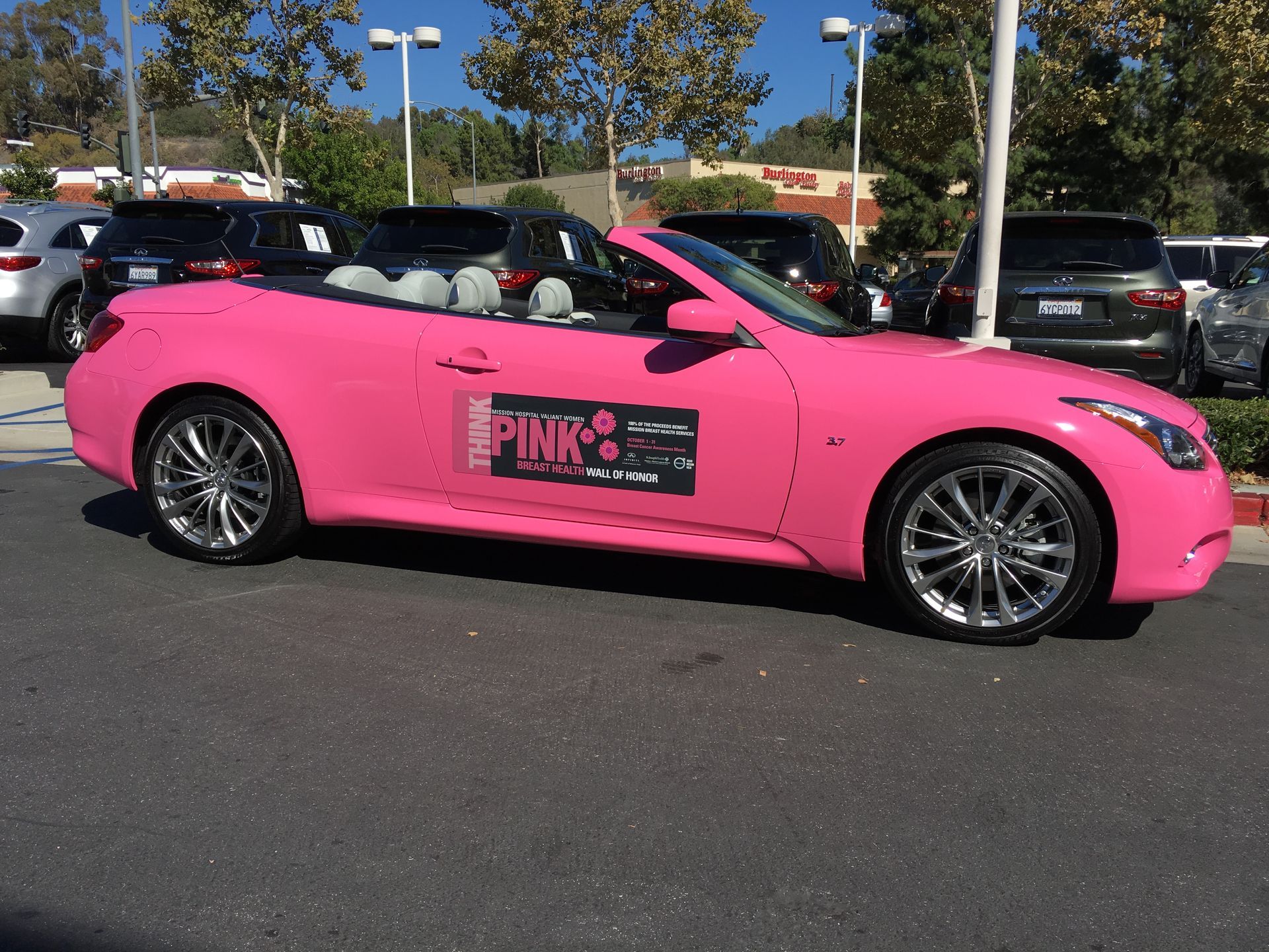 A pink car is parked in a parking lot