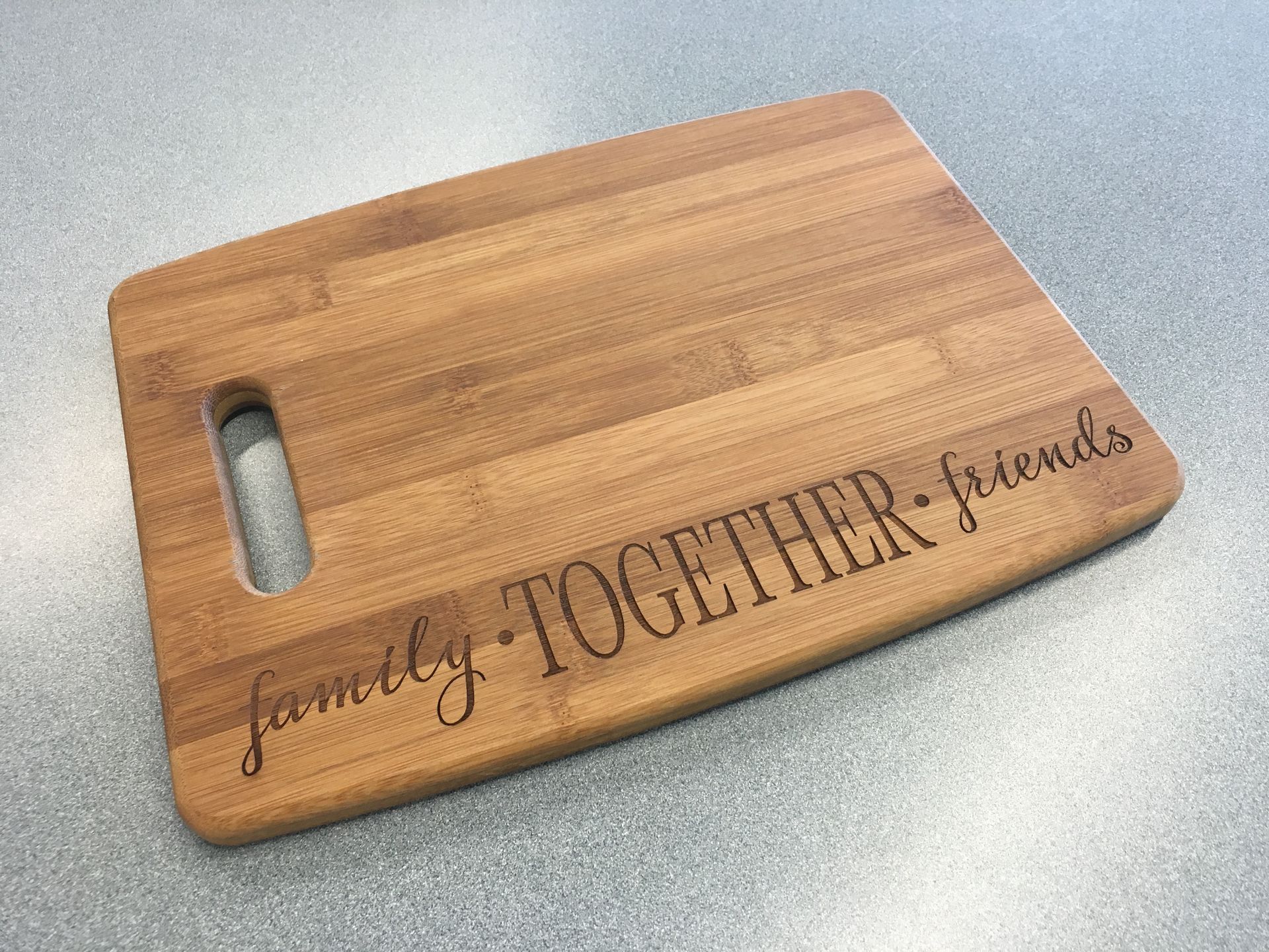 A wooden cutting board with the words `` family together friends '' engraved on it.
