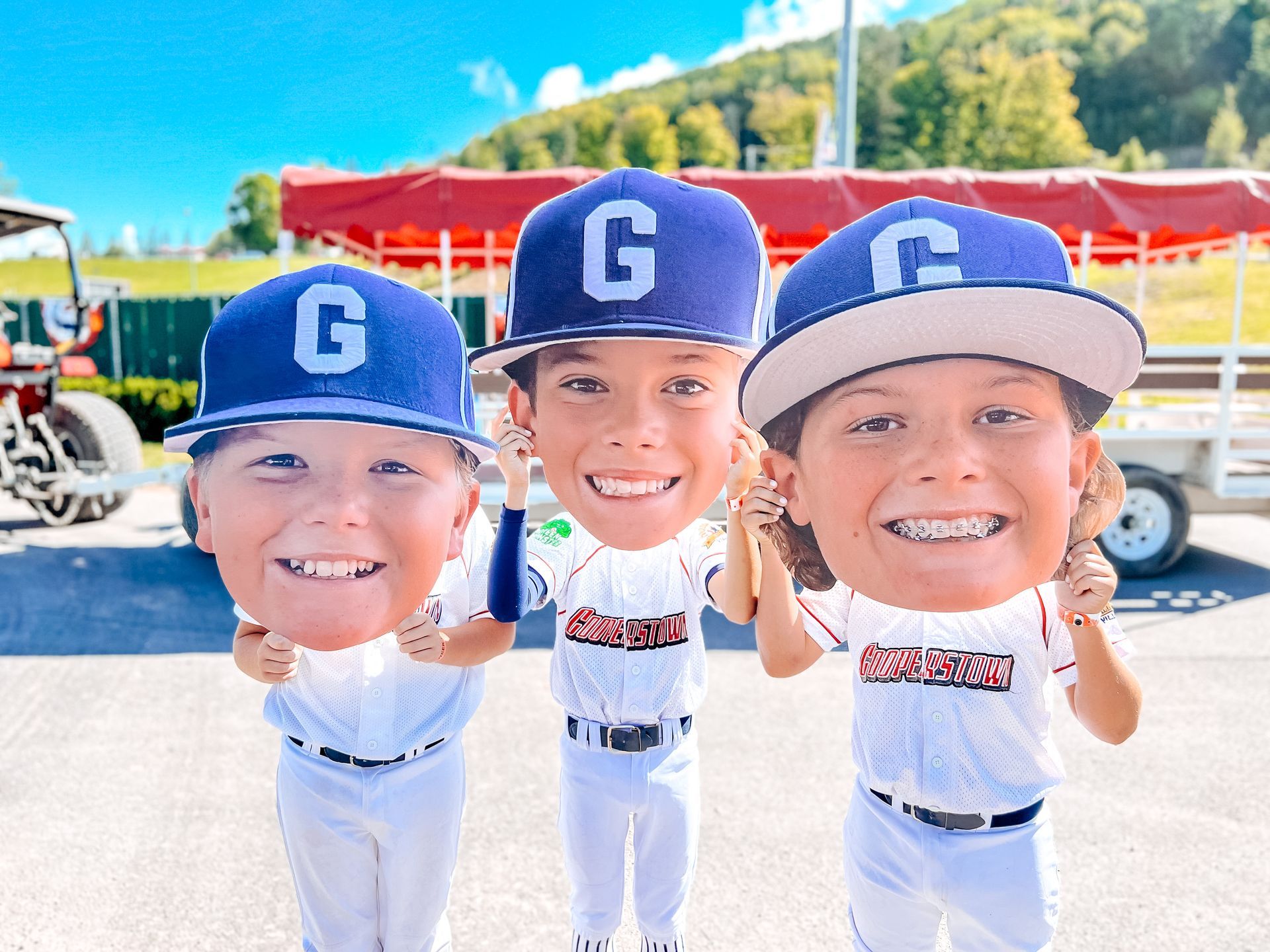 Three young boys wearing baseball uniforms and hats are posing for a picture.