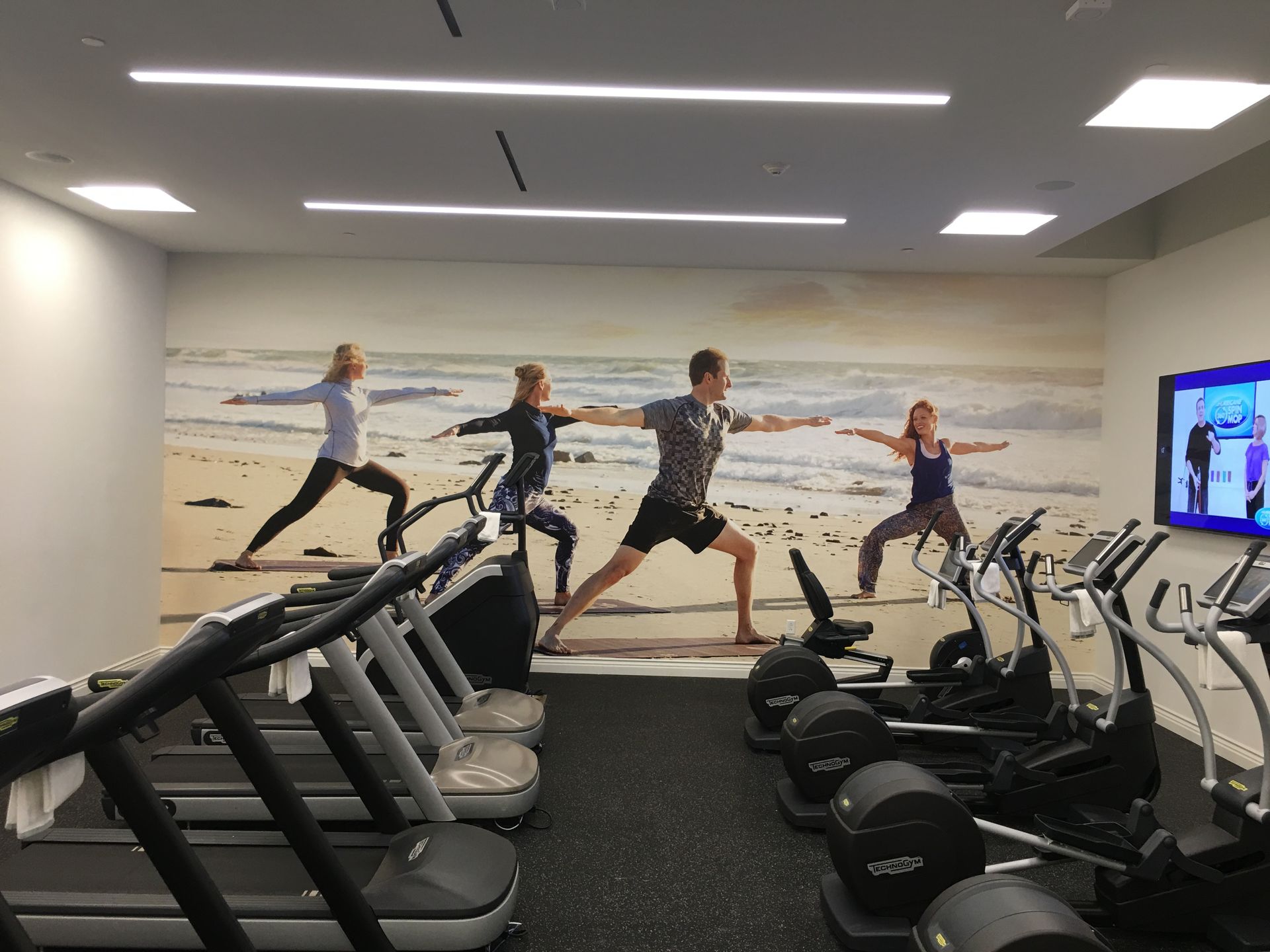 A gym with a picture of people doing yoga on the wall.