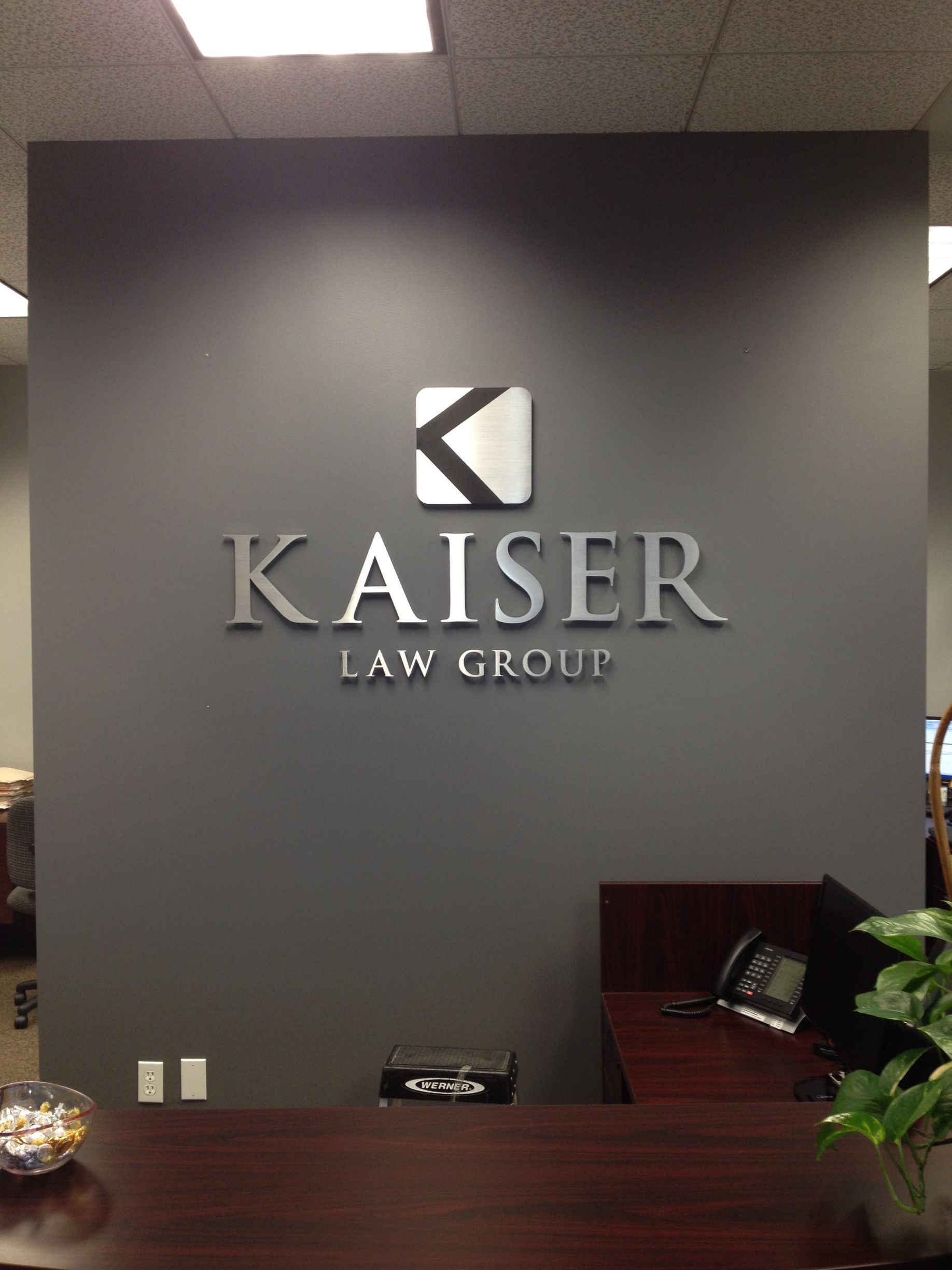 A kaiser law group sign on a wall above a desk