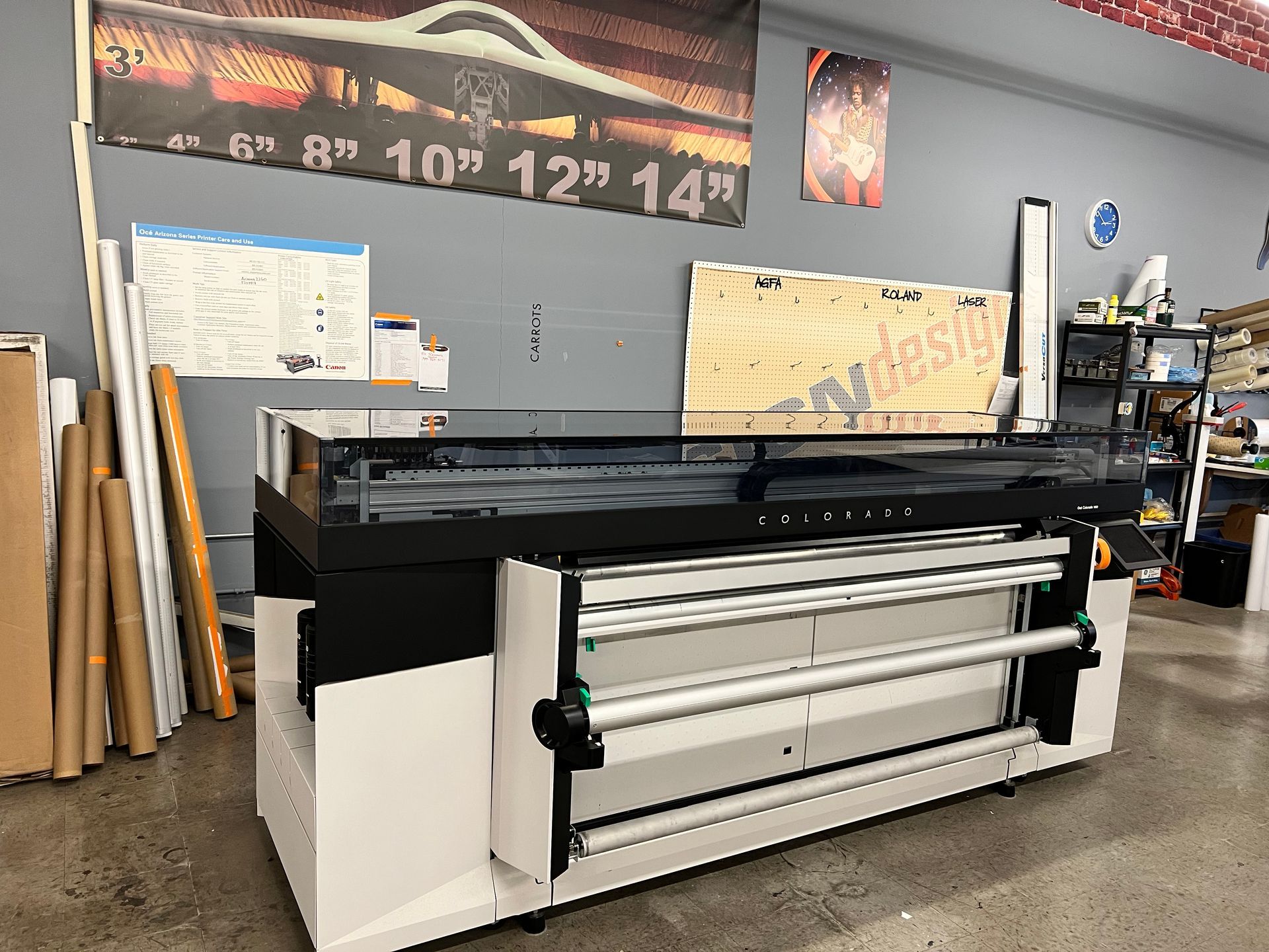 A large printer is sitting in a room with a sign on the wall.