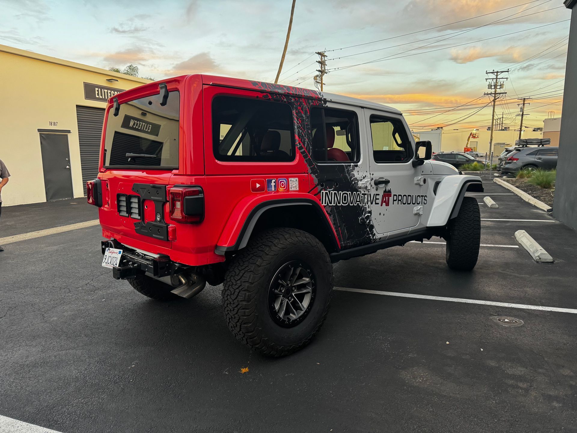 A red and white jeep is parked in a parking lot.