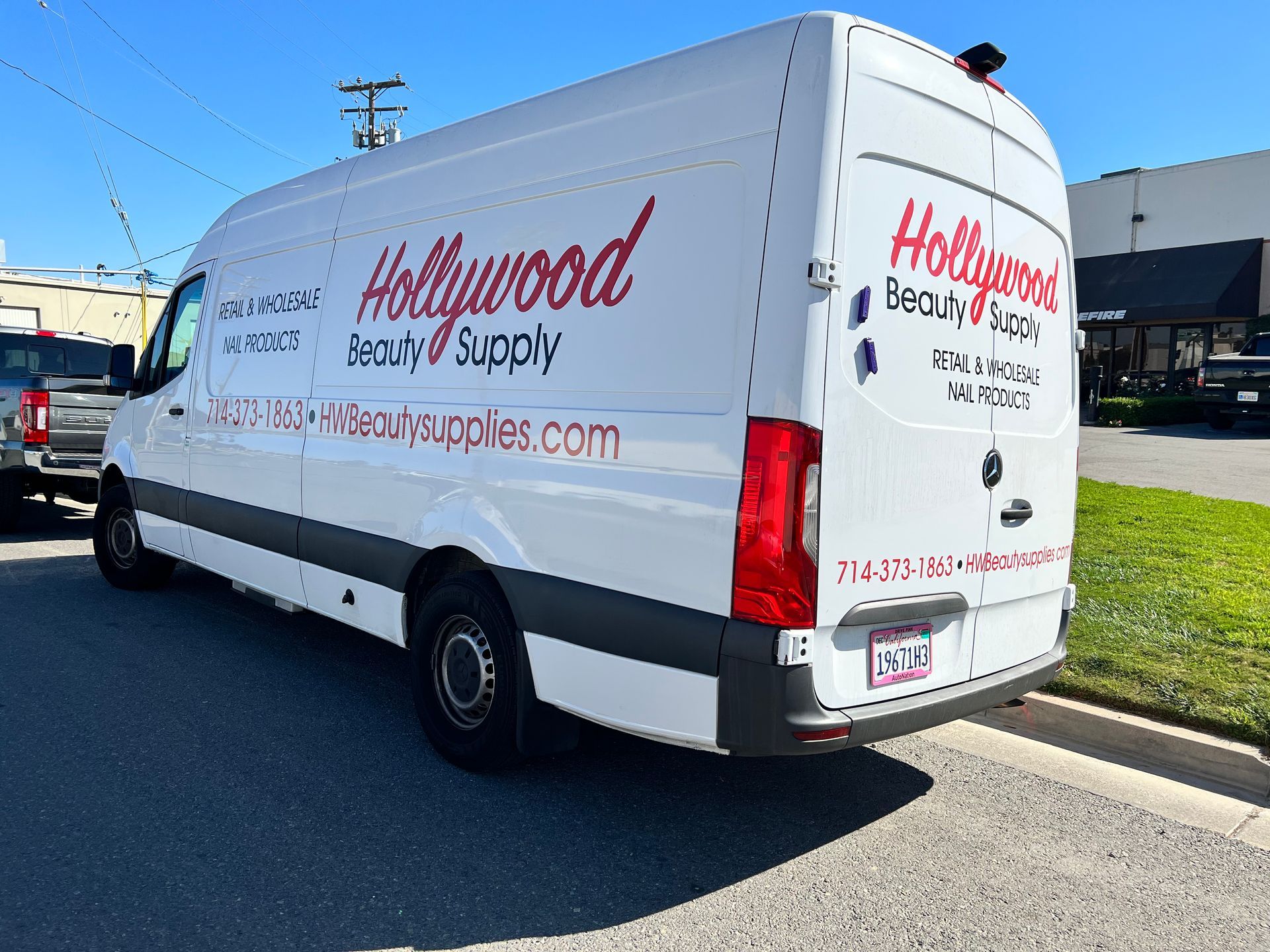 A hollywood beauty supply van is parked on the side of the road.