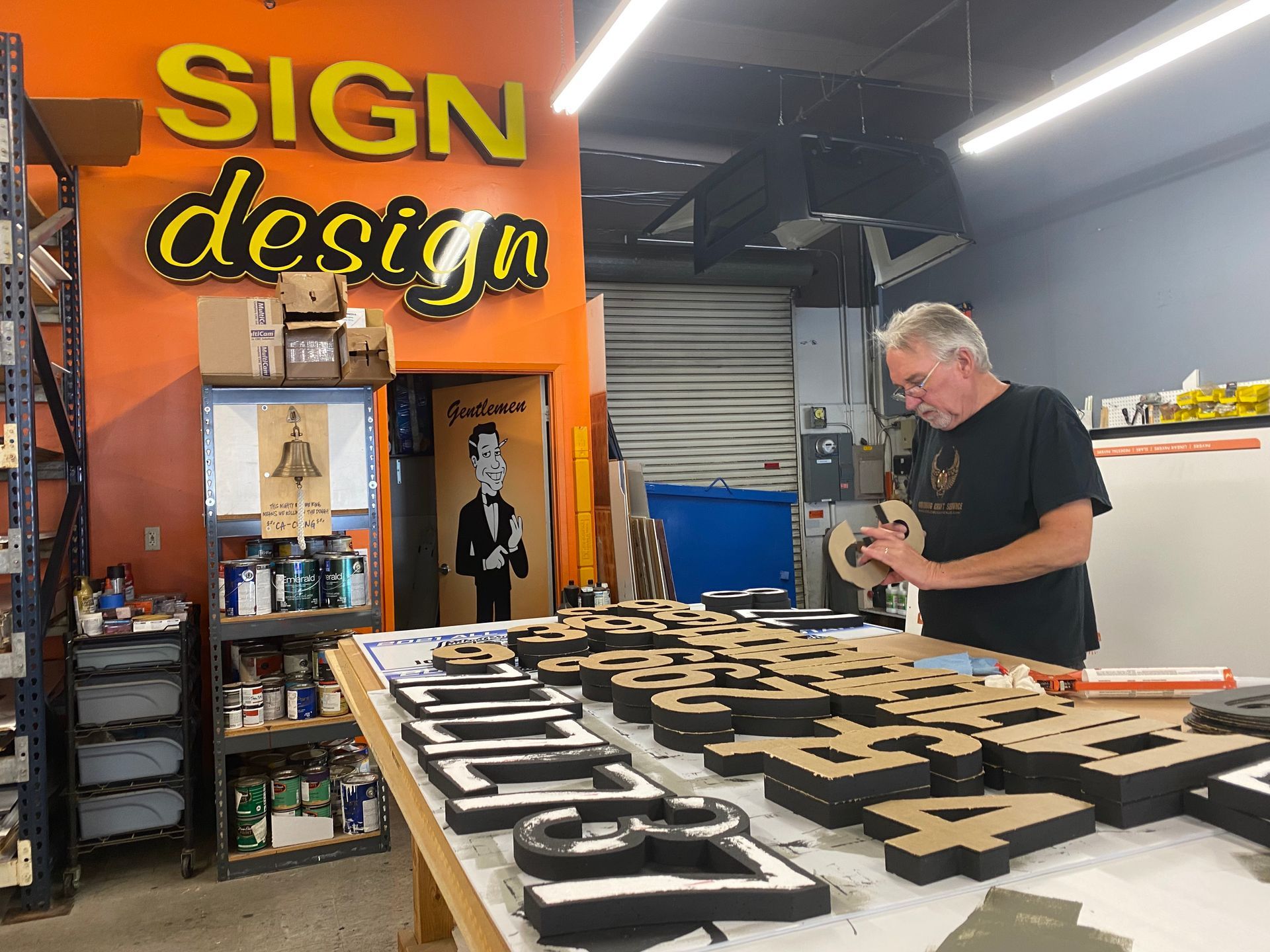 A man is working on a sign in a sign design studio.