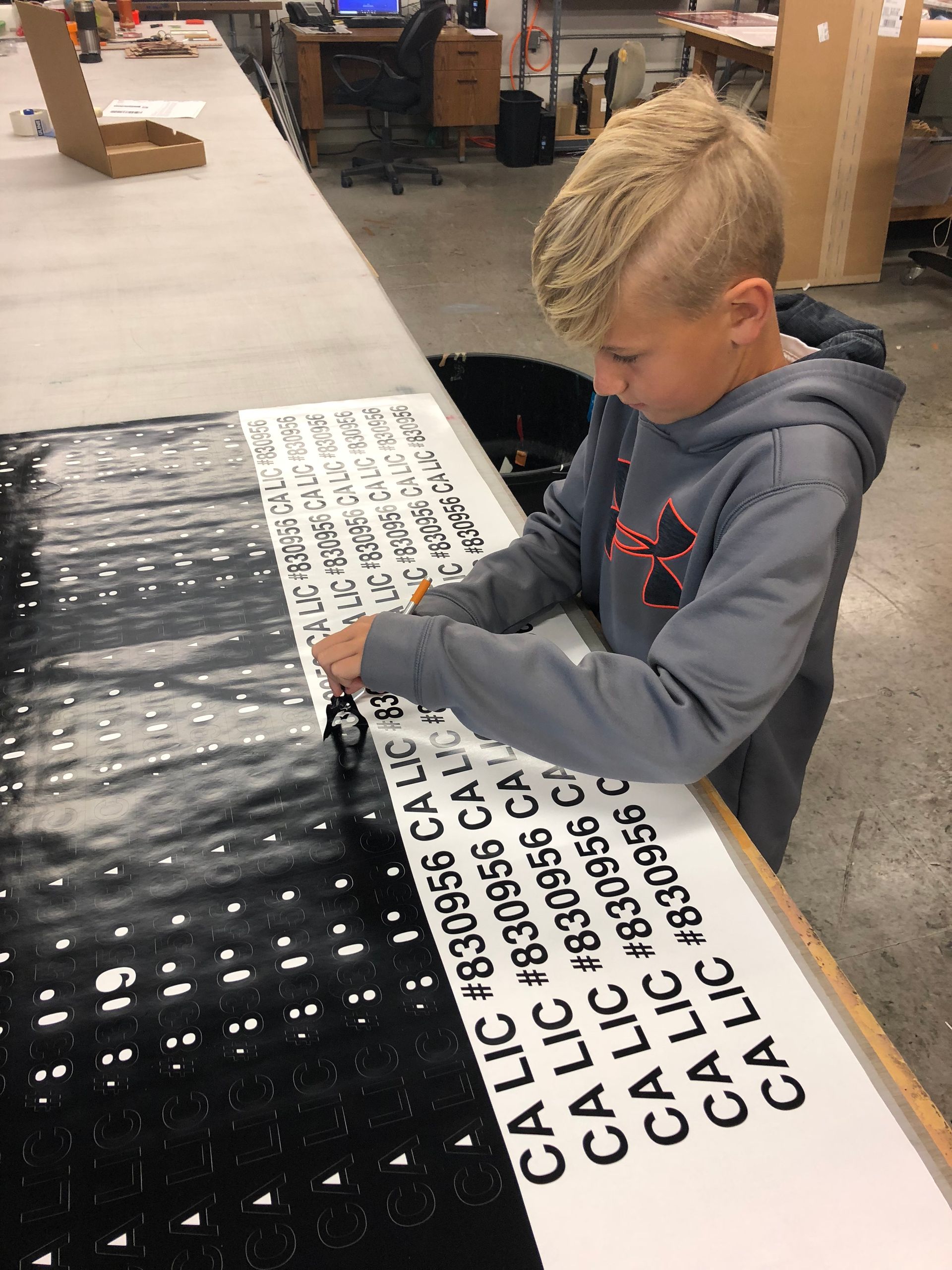 A young boy is working on a piece of paper that says calic on it