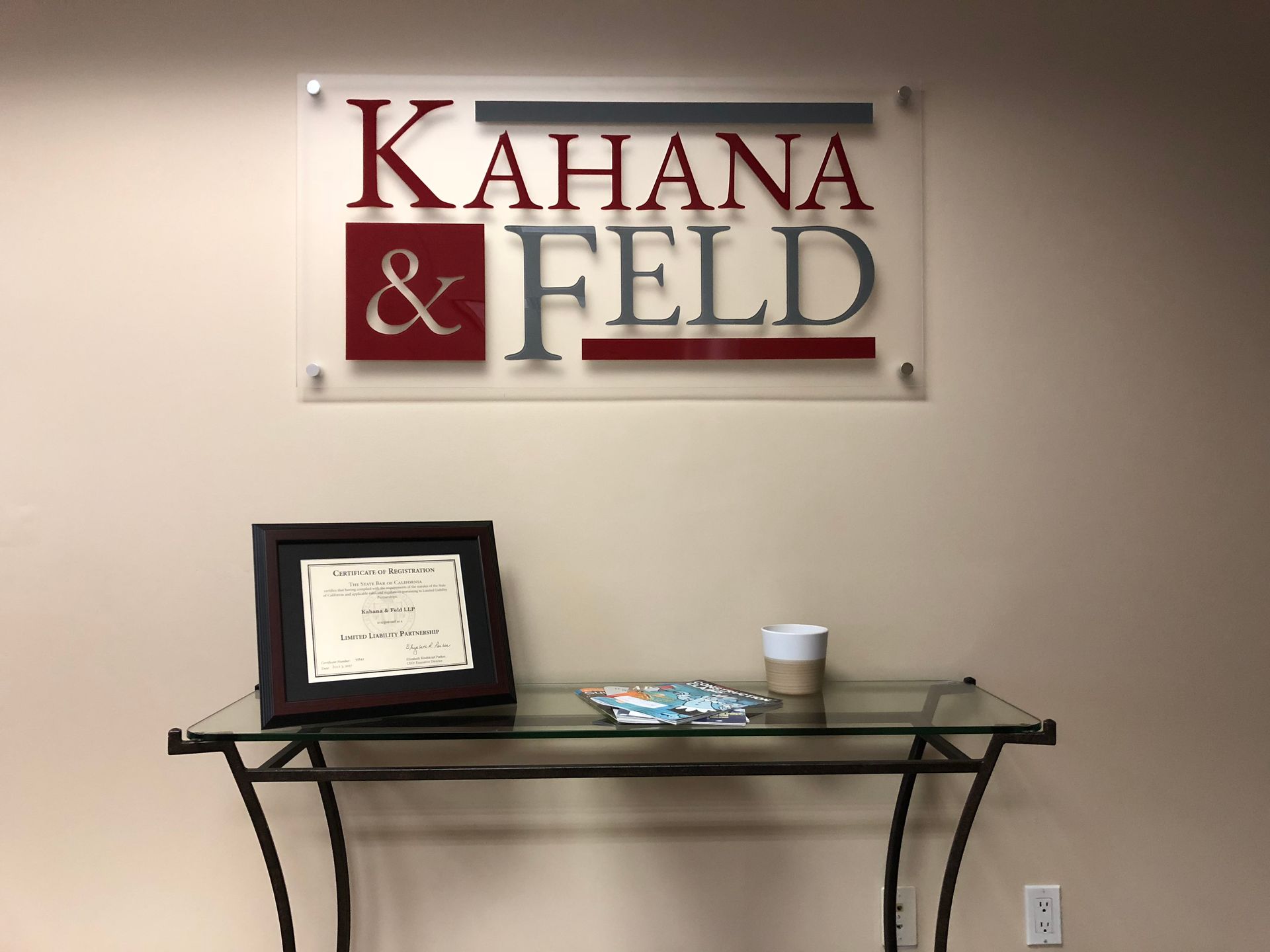 A sign for kahana & feld hangs above a glass table