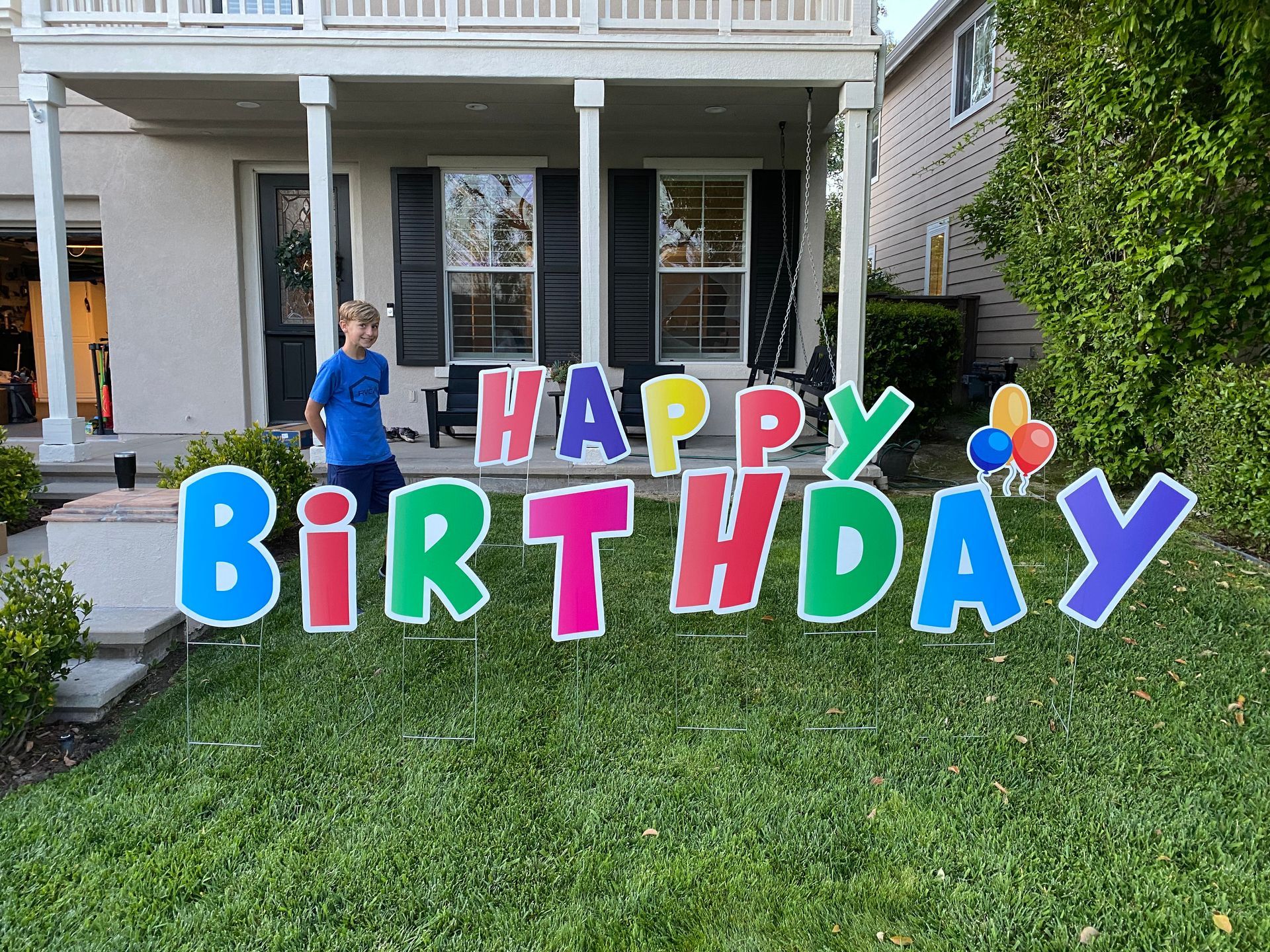 A boy is standing in front of a happy birthday sign