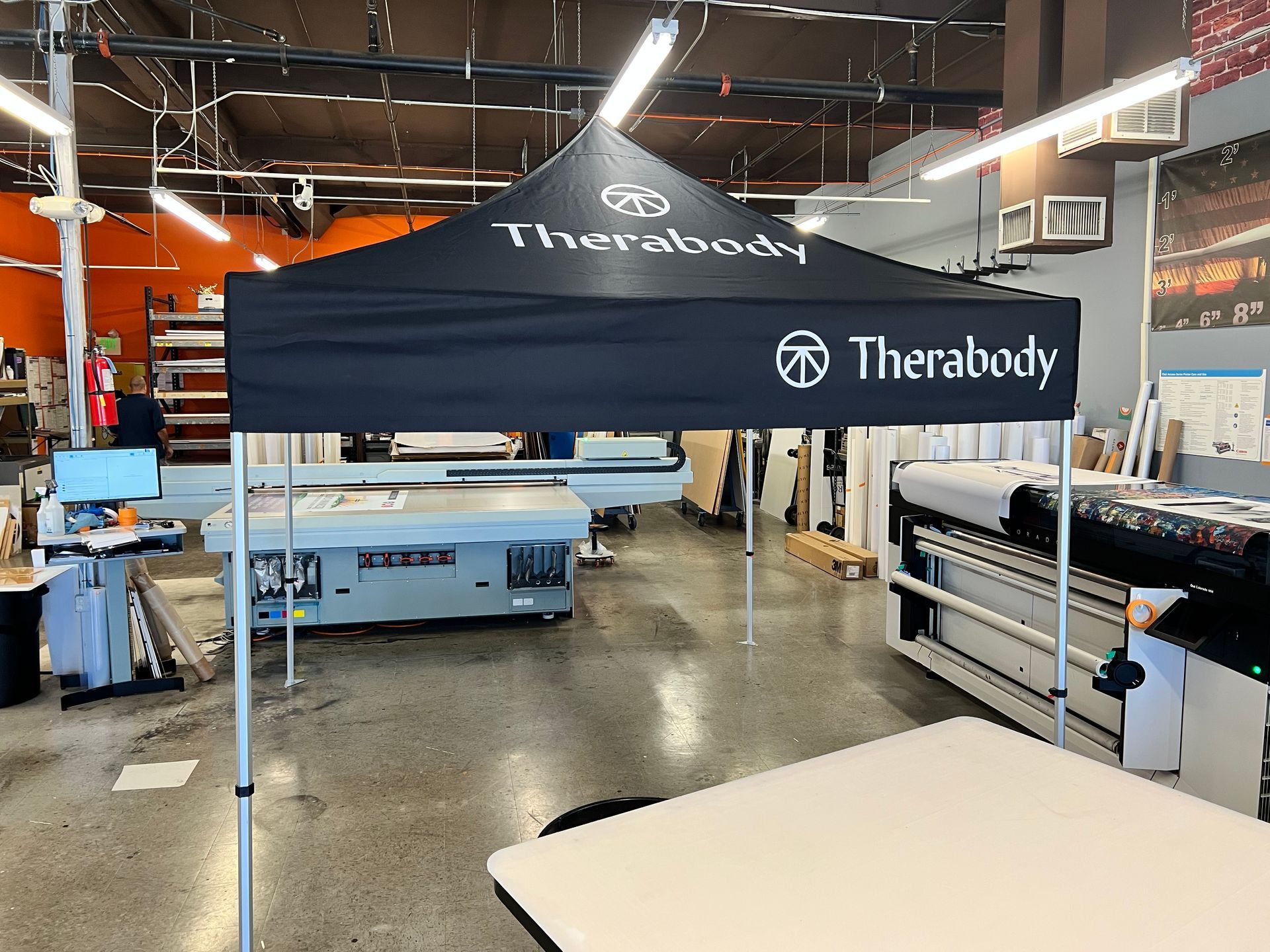 A black tent with the word therabody on it is in a warehouse.