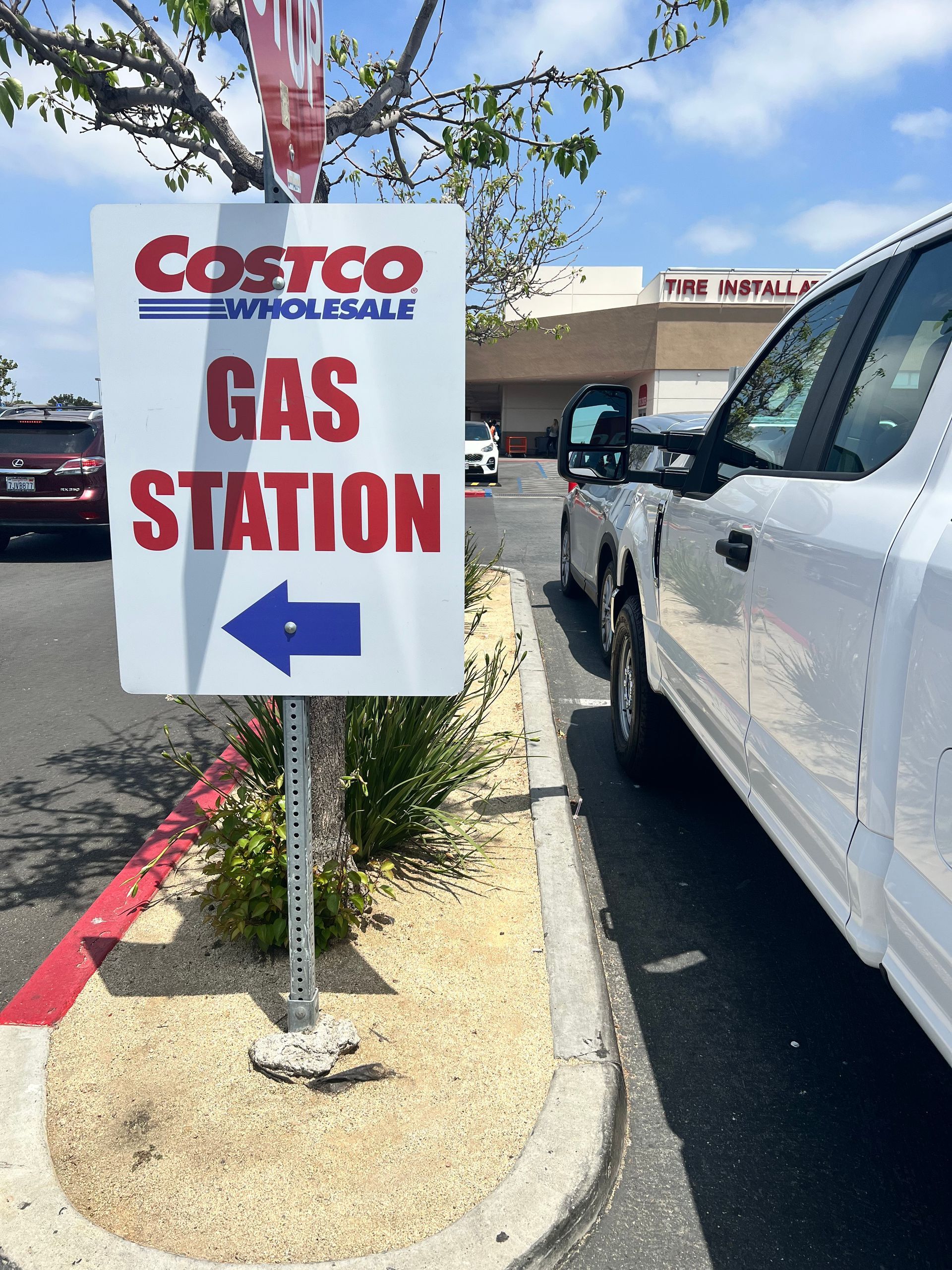 A white truck is parked in front of a costco gas station sign