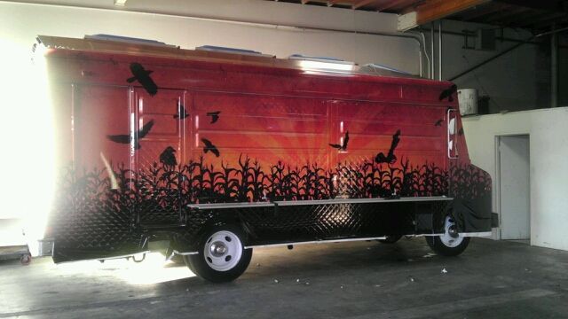 A red van with black birds painted on it is parked in a garage.