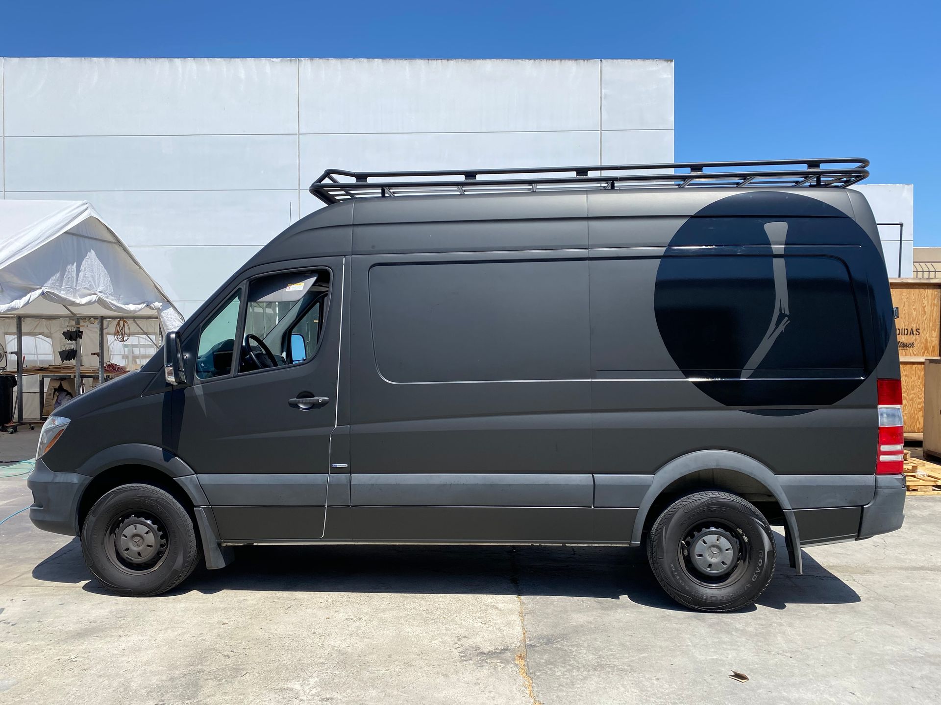 A black van with a roof rack is parked in front of a building.