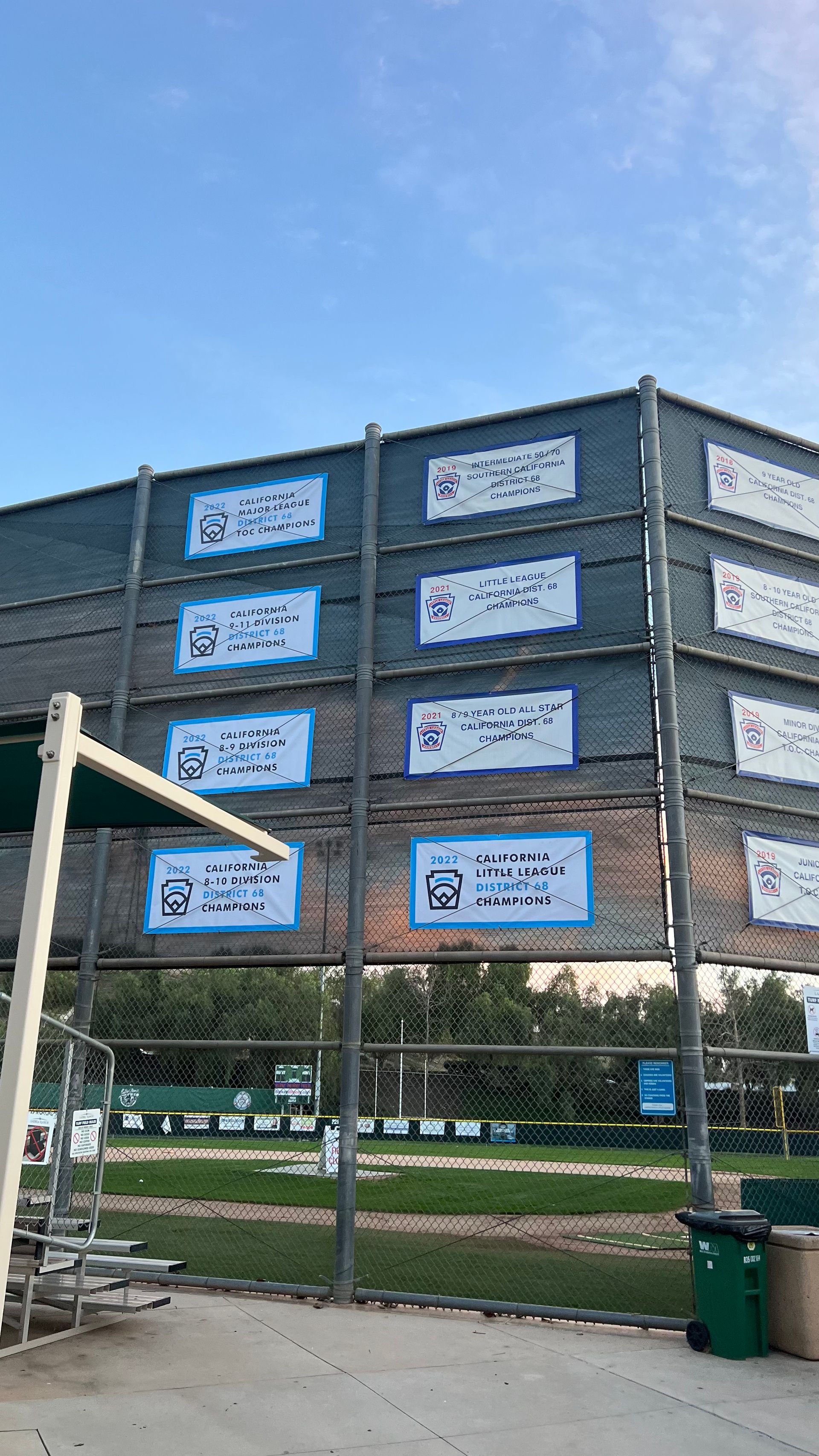A fence with a lot of signs on it in a park.