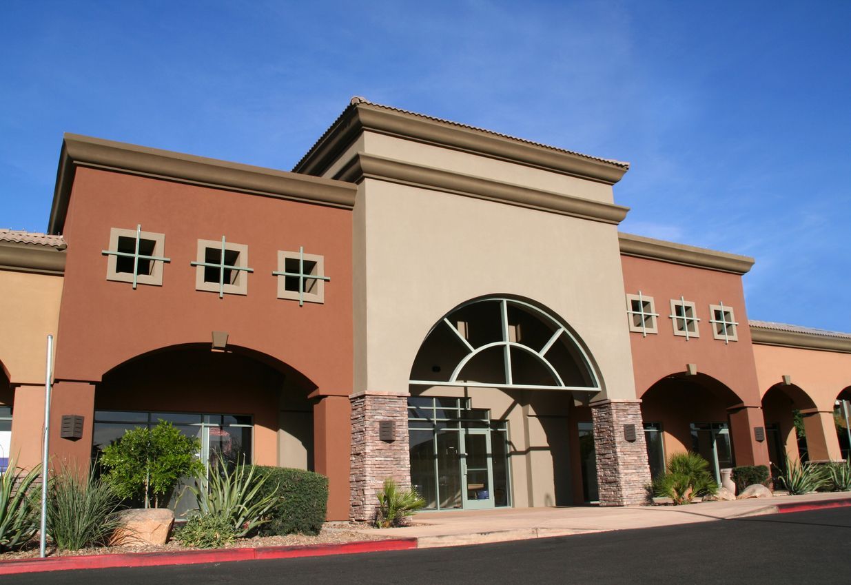 Commercial building with stucco facade and arched entrance.