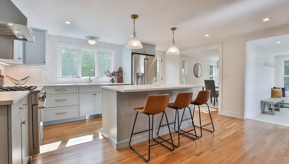 Modern kitchen with gray cabinets, white countertops, and a kitchen island with bar stools.