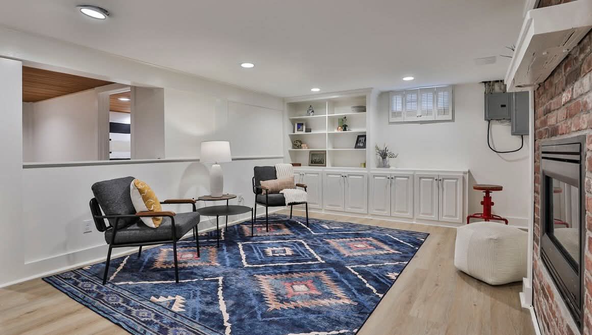 Modern living room with blue rug, white walls, built-in shelving, and fireplace.