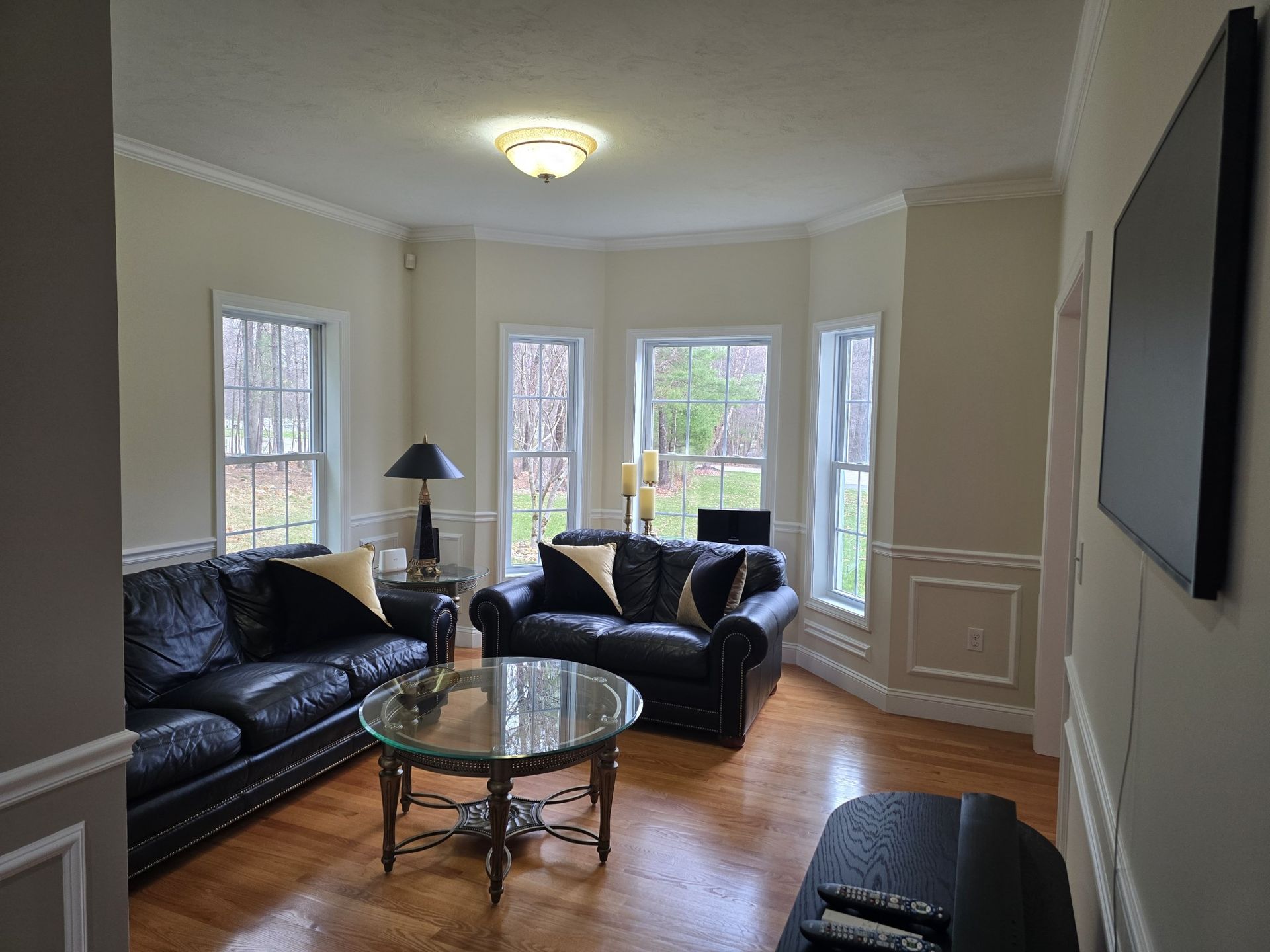 Living room with black leather sofas, a round coffee table, and windows.