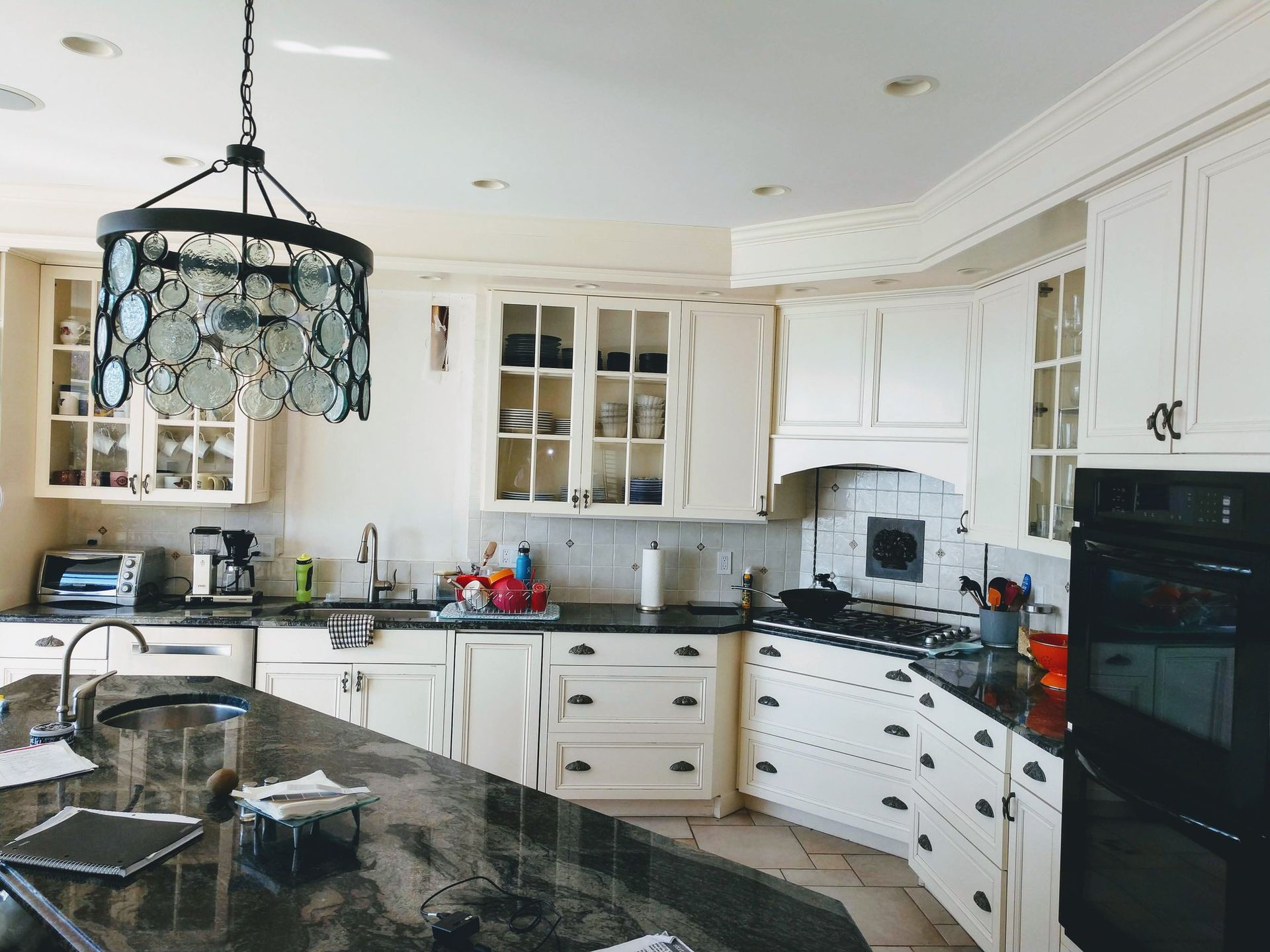 Kitchen with white cabinets, dark countertops, and a decorative light fixture.