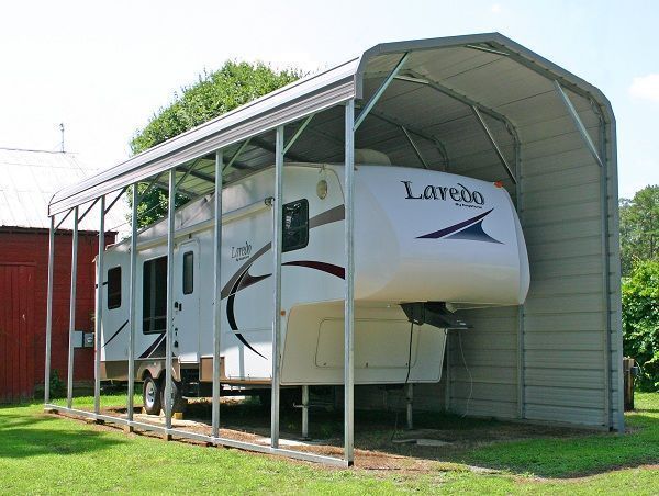 RV parked under a steel carport in a grassy yard.