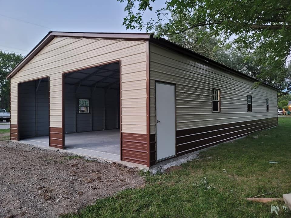 Tan and brown metal garage with two bays, a door, and two windows; concrete pad, grass.
