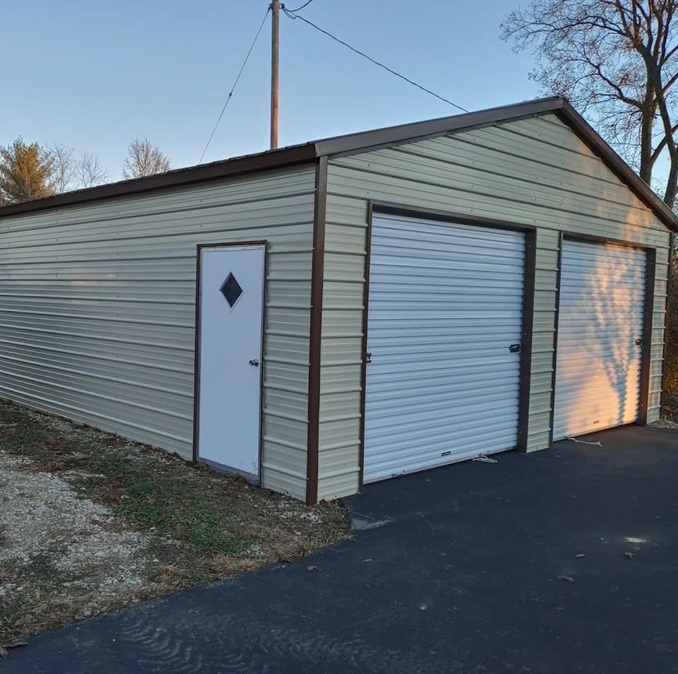 Tan metal garage with brown trim, two garage doors, and a side door on a paved driveway.