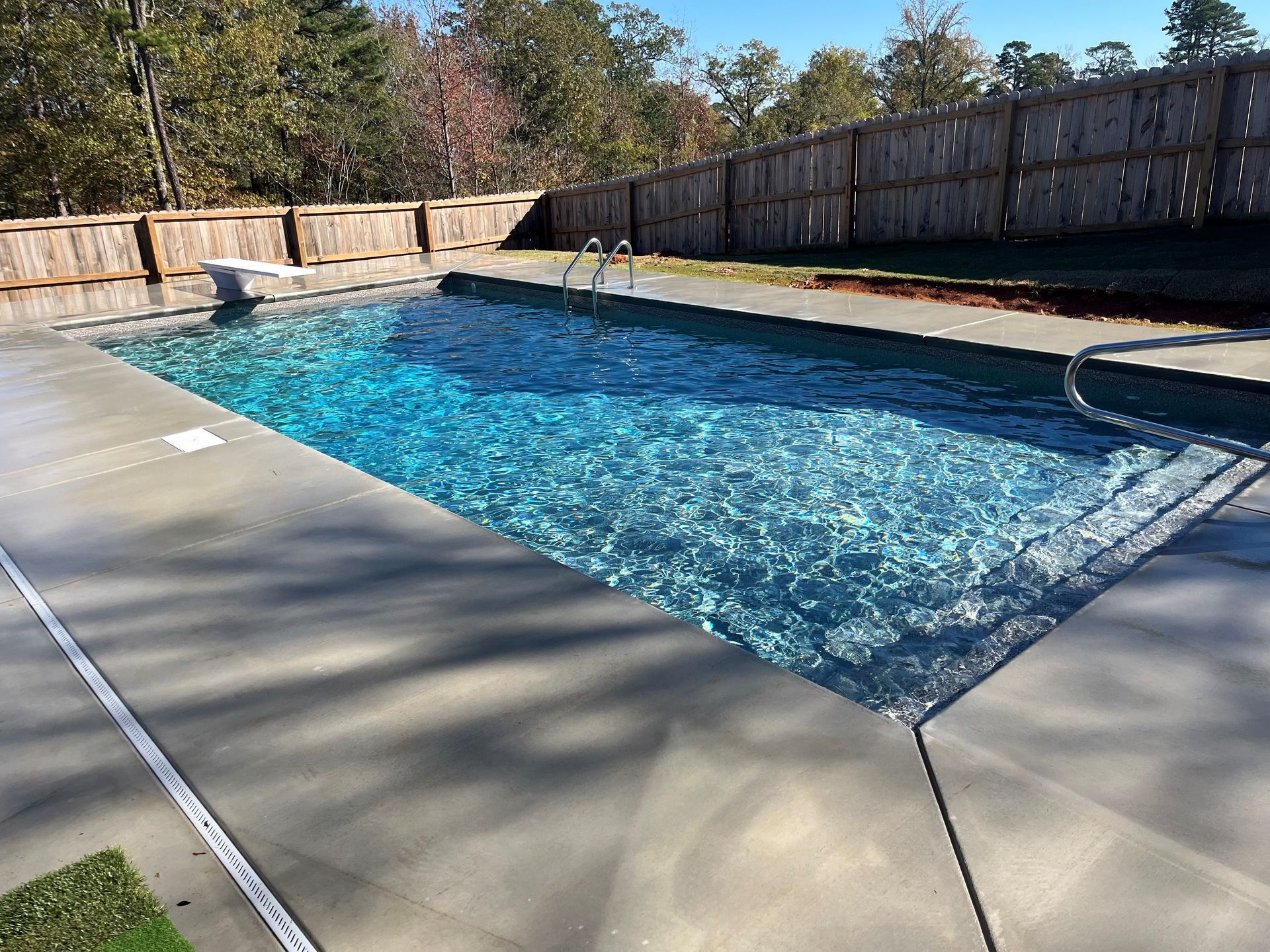 A large swimming pool is surrounded by a wooden fence